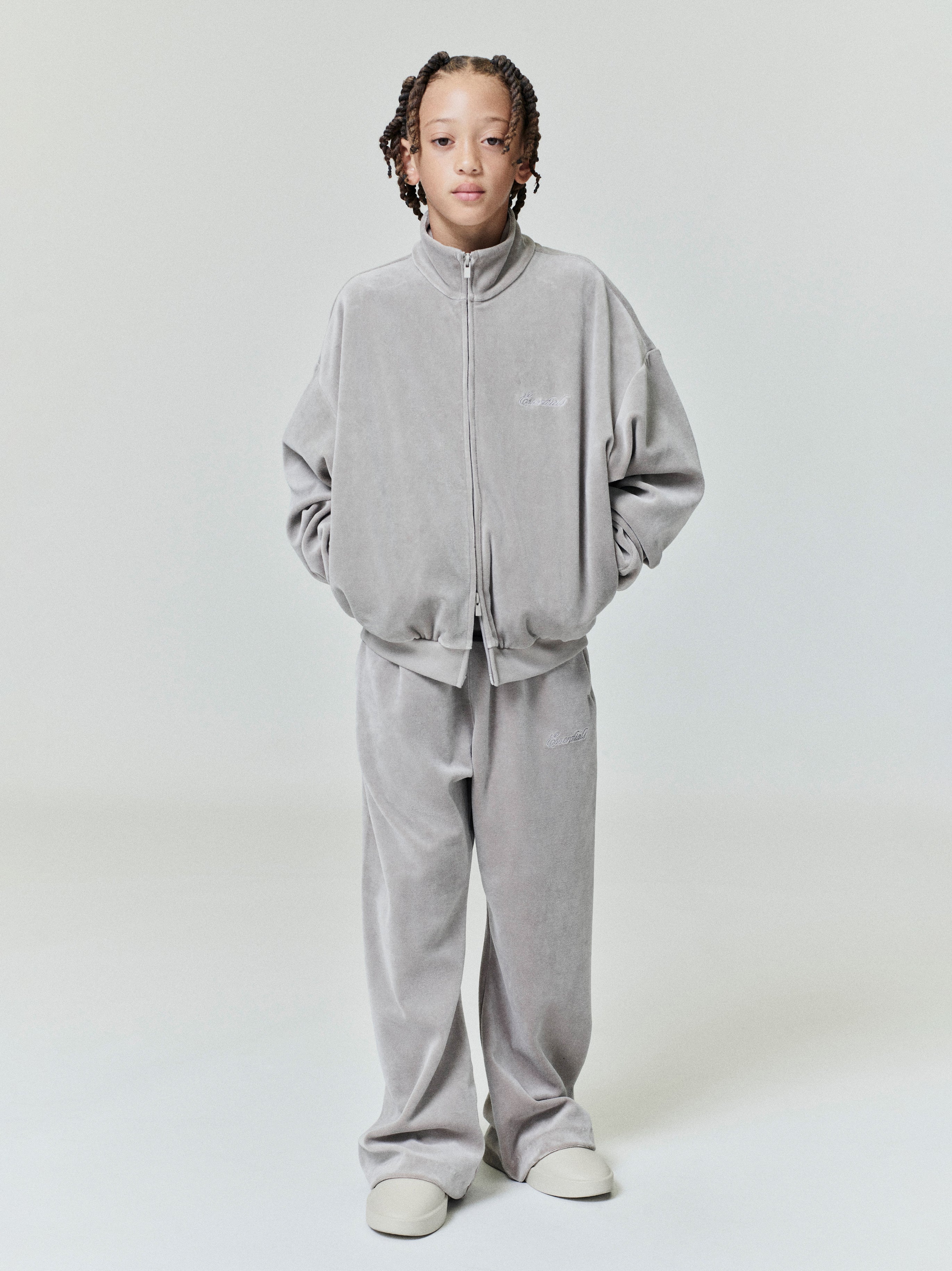 Child wearing light gray velour zip-up jacket and matching wide-leg velour sweatpants standing with hands in pockets
