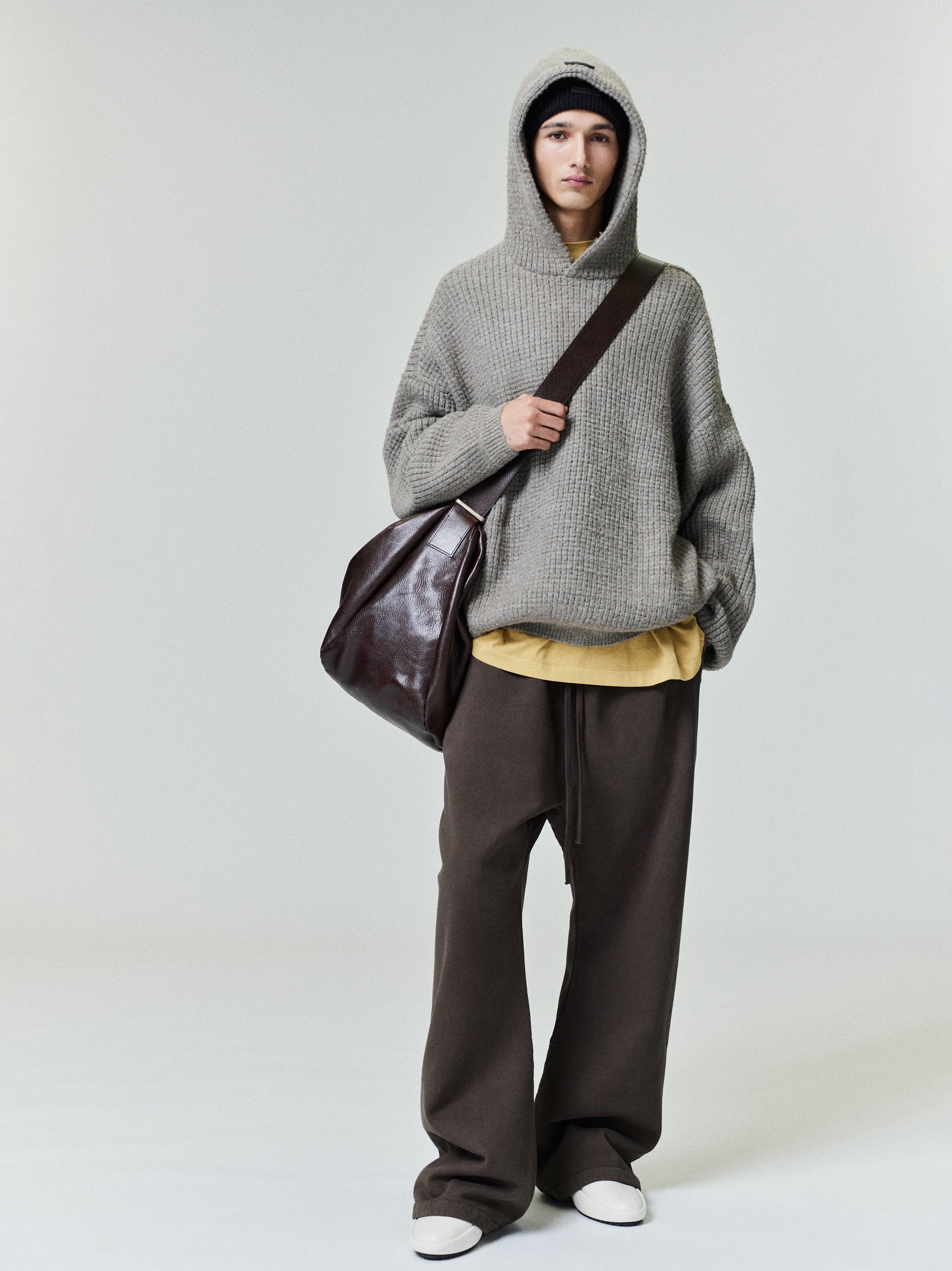Model wearing dark brown Heavy Fleece Flare Sweatpant paired with oversized gray knit hoodie and dark leather shoulder bag, gallery 0