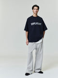 Male model wearing black Ponte 90s Tee with distorted white Fear of God Essentials logo, standing with hands in pockets, gallery 0