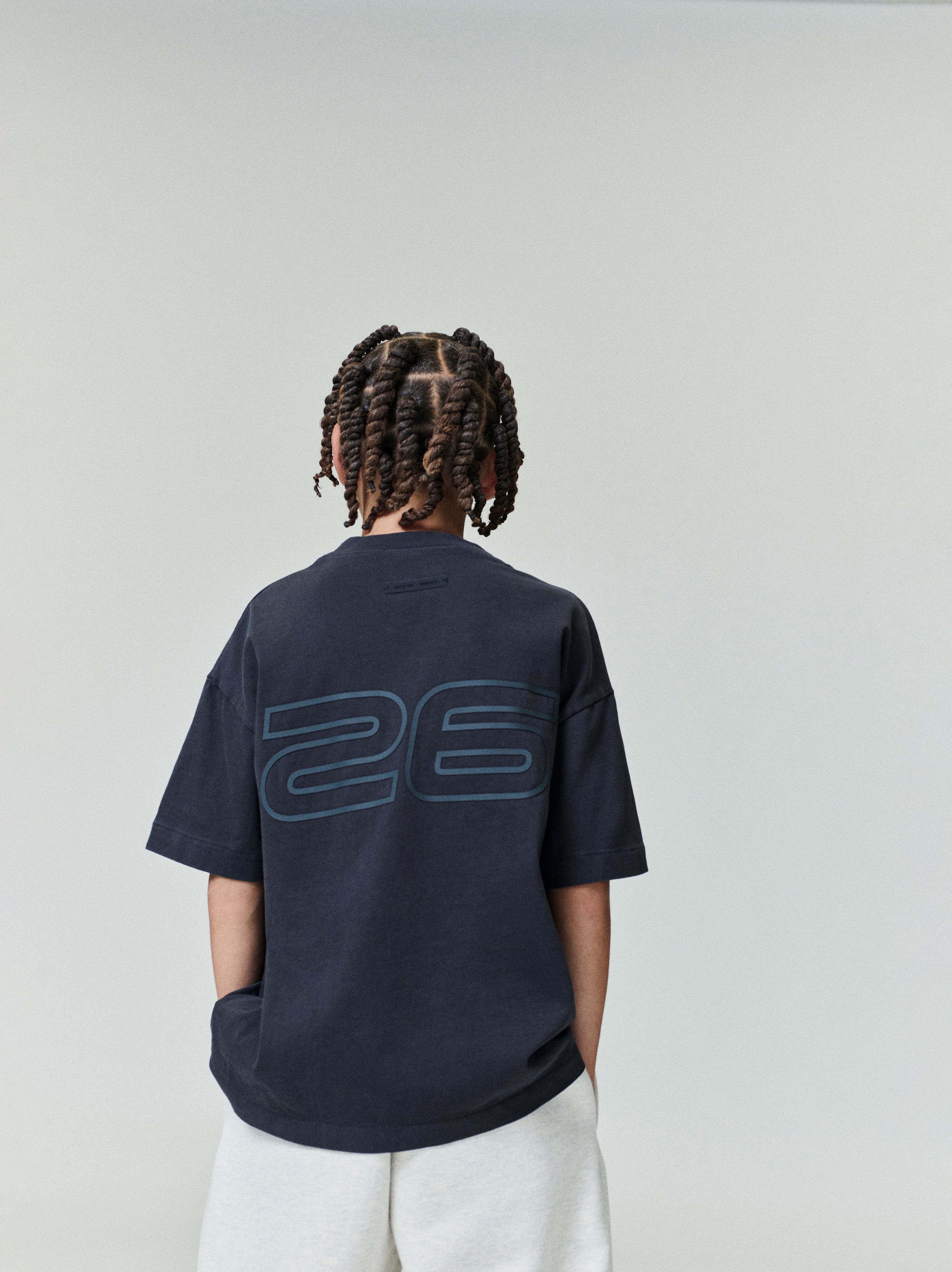 Child shown from back wearing navy Kids Classic Short Sleeve Tee with large subtle "26" print, gallery position 0, file 0007_HO25_K_L75_4009.jpg