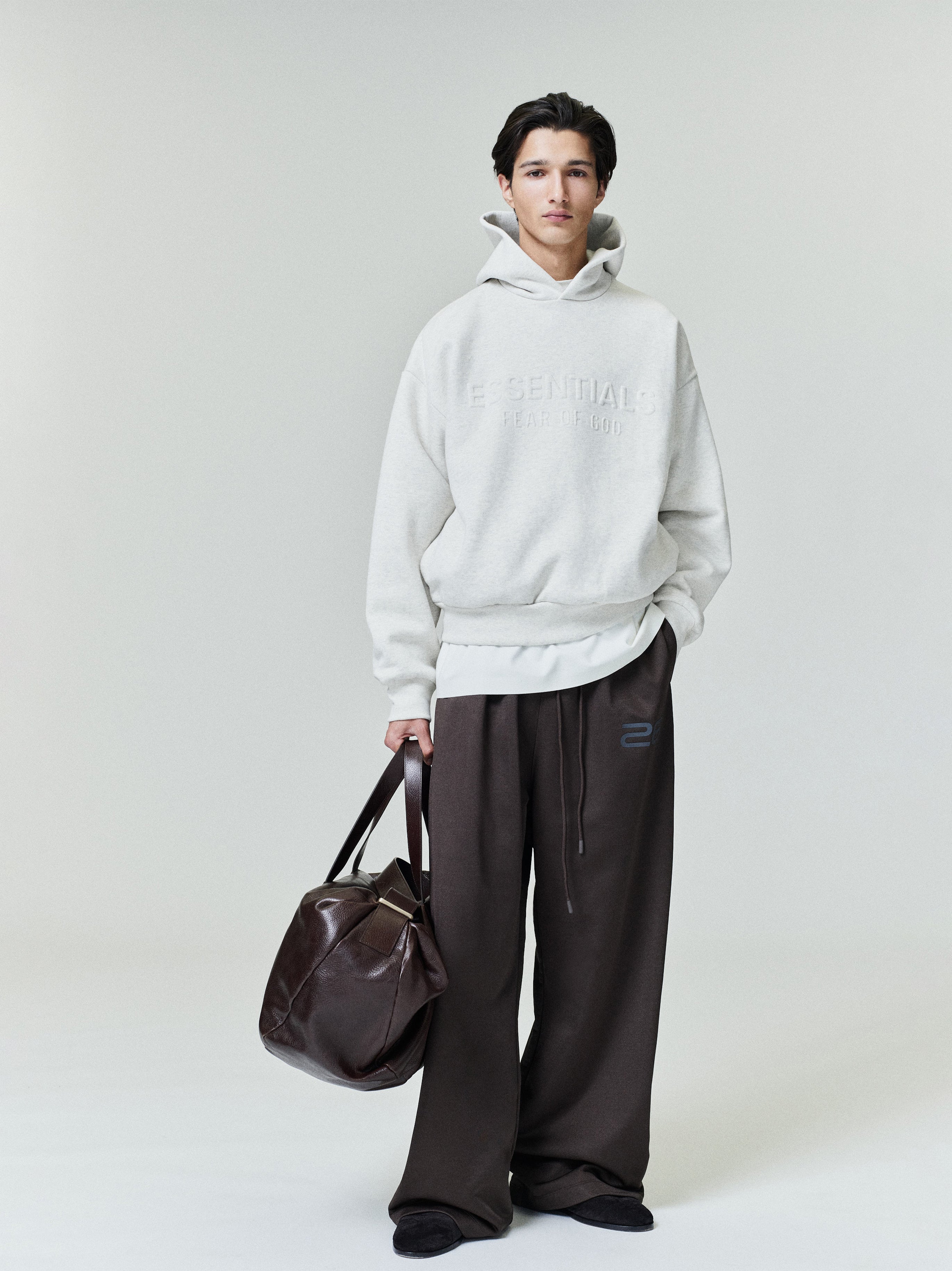 Model standing in satin fleece lounge sweatpants and light hoodie holding dark brown leather bag gallery 0 file 0009_HO25_F_L28_P30_3342copy.jpg