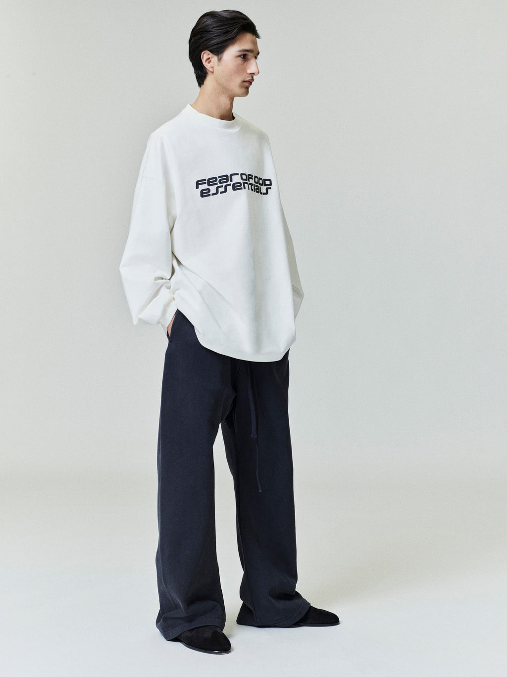 Model wearing oversized white Ponte 90s Long Sleeve Tee with bold Fear of God Essentials logo across chest, gallery 0 0010_HO25_F_L80_4346.jpg