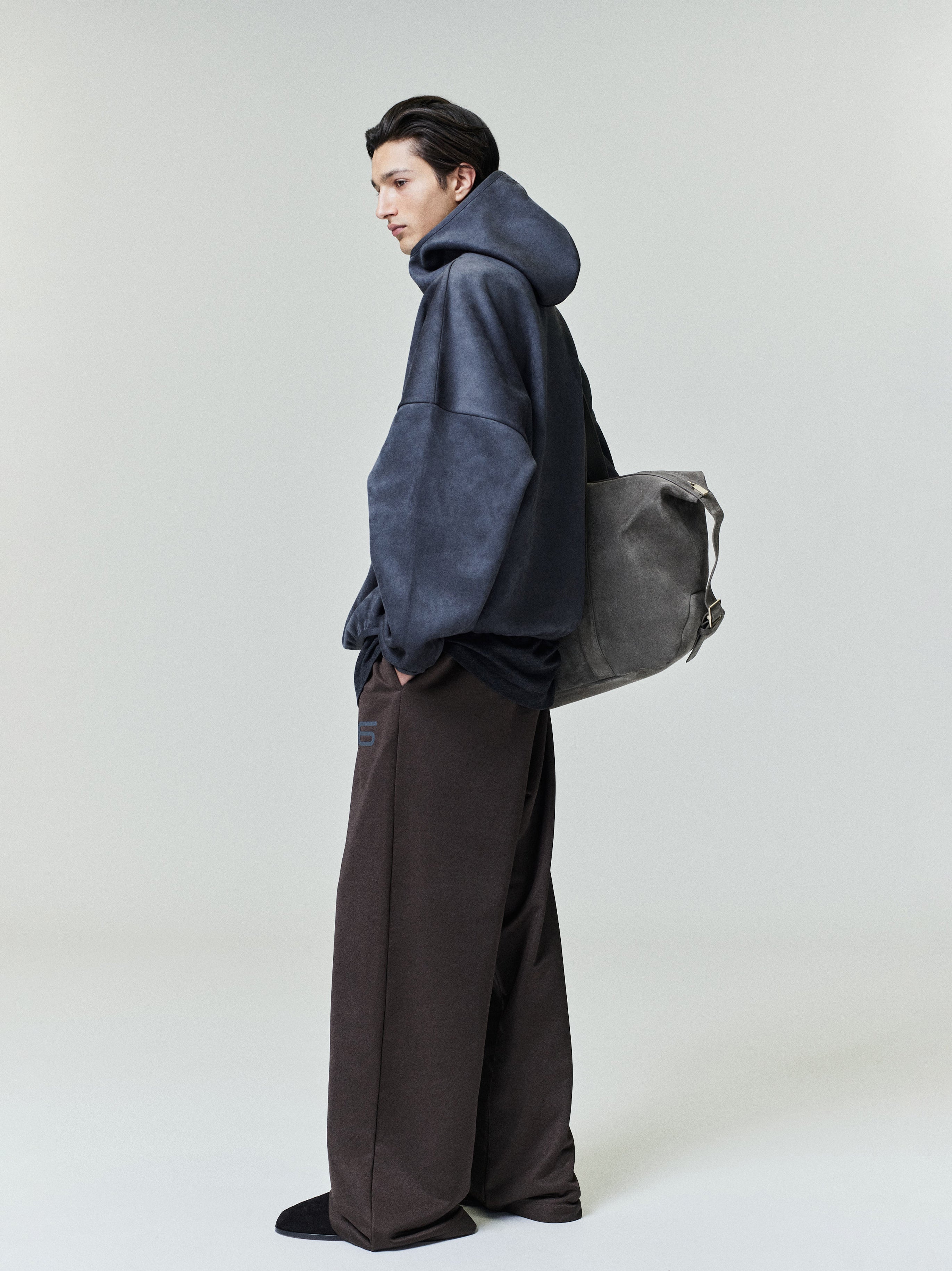 Side profile of model wearing navy suede fleece modern hoodie with wide black pants and gray suede backpack 0012_HO25_F_L26_3195copy.jpg