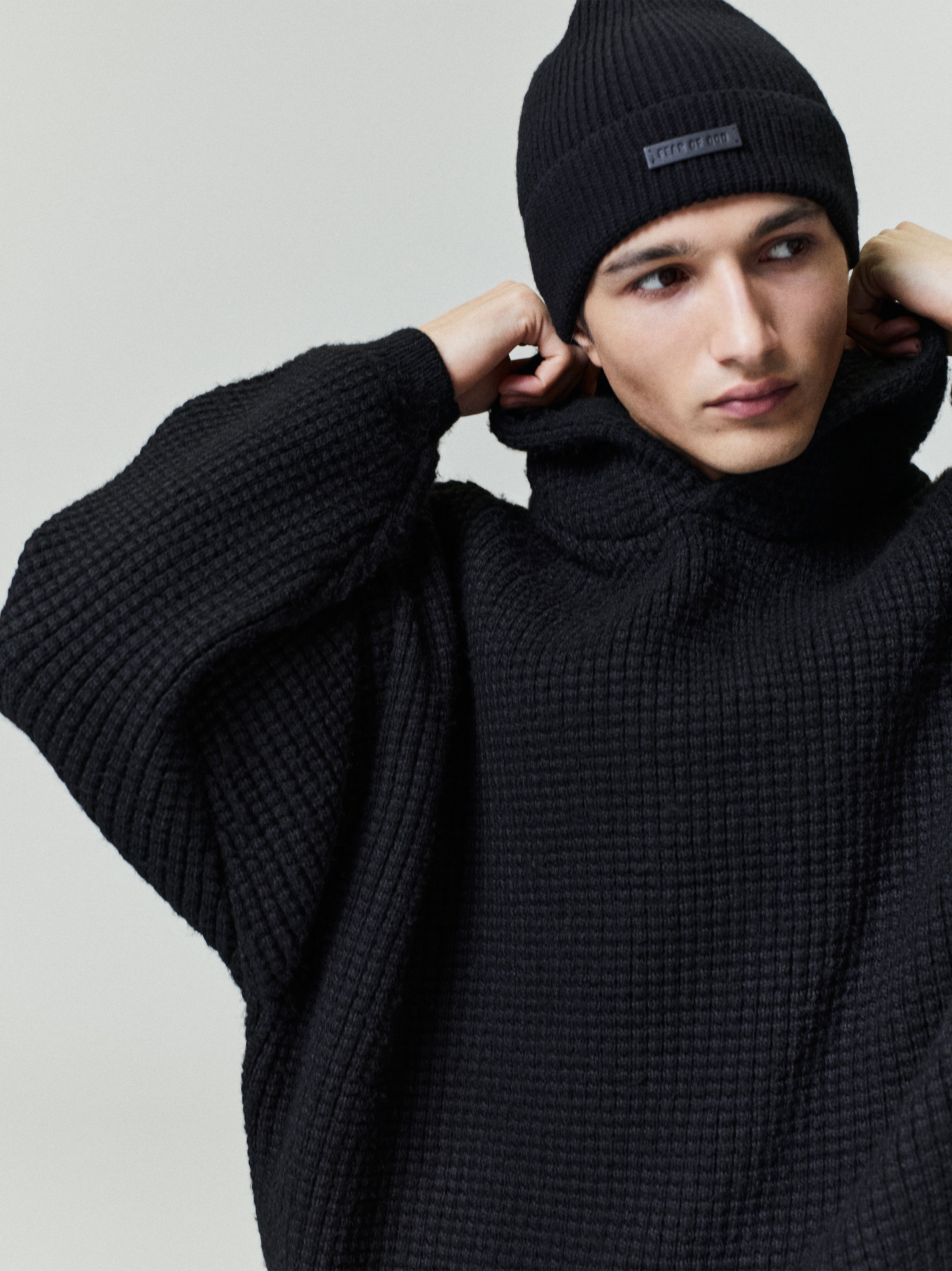 Close-up of model adjusting hood wearing black Heavy Waffle 90s Hoodie with distinctive textured knit fabric