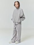 Full-length view of kid wearing light gray velour flare sweatpant and matching oversized zip-up jacket on plain background