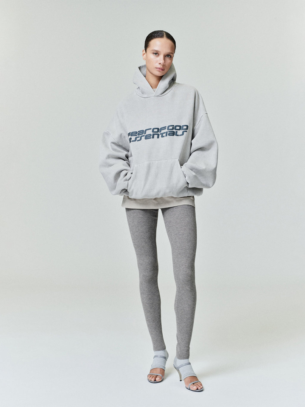 Full body view of model wearing light gray Heavy Fleece 90s Hoodie with bold Fear of God Essentials logo 0029_HO25_FW_L10_P31_1161copy.jpg