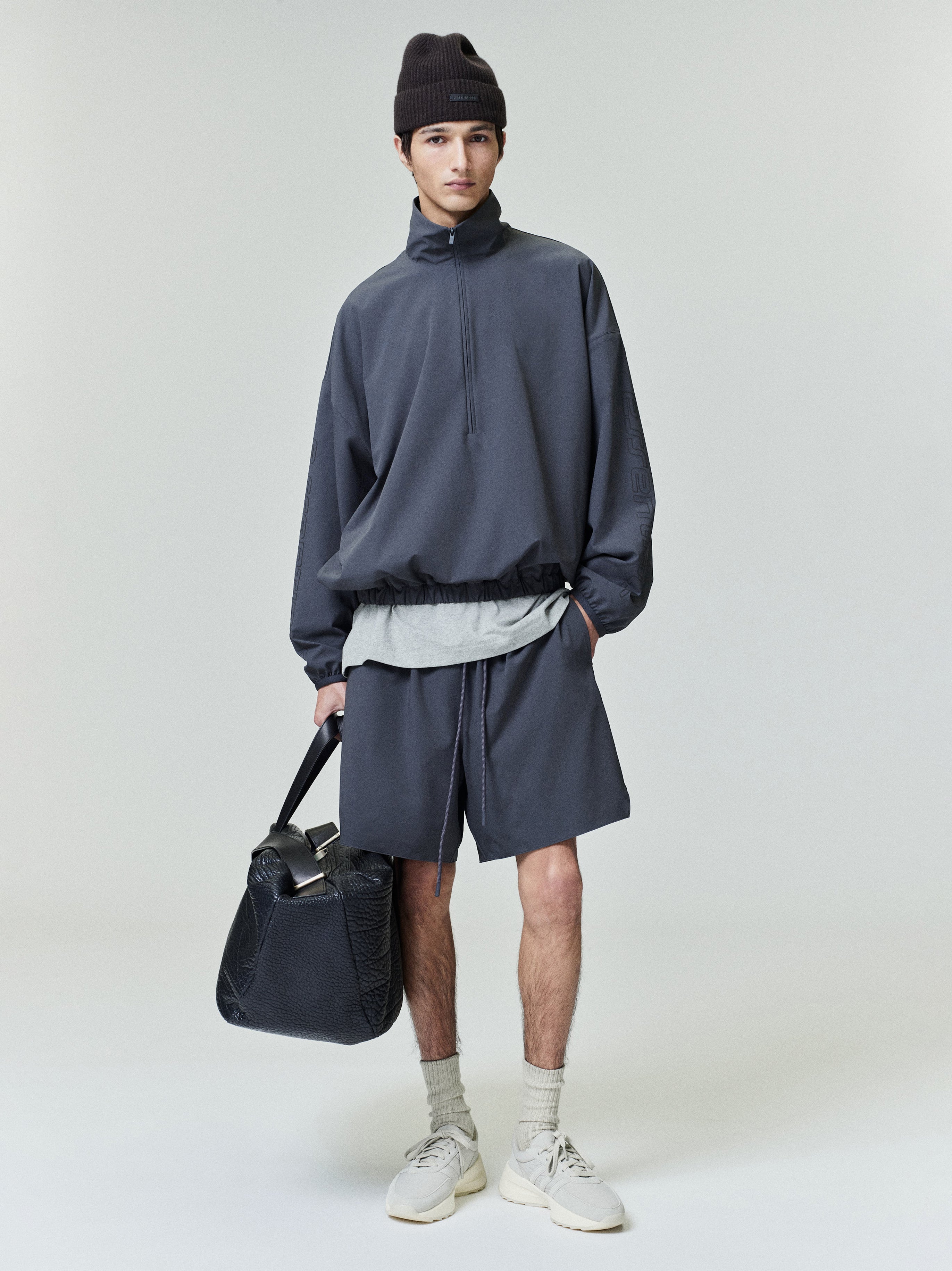 Model wearing dark iron grey Tech Nylon Classic Shorts paired with oversized pullover and black textured leather bag