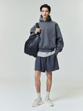 Model wearing dark charcoal Embossed Essentials Classic Hoodie with matching shorts and carrying large black textured bag