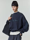 Male model wearing navy Los Angeles heavy fleece cropped sweatshirt with black beanie and large textured leather tote bag