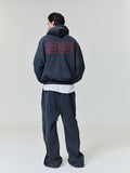 Person wearing a dark grey tracksuit with a large red '26' on the back against a white background