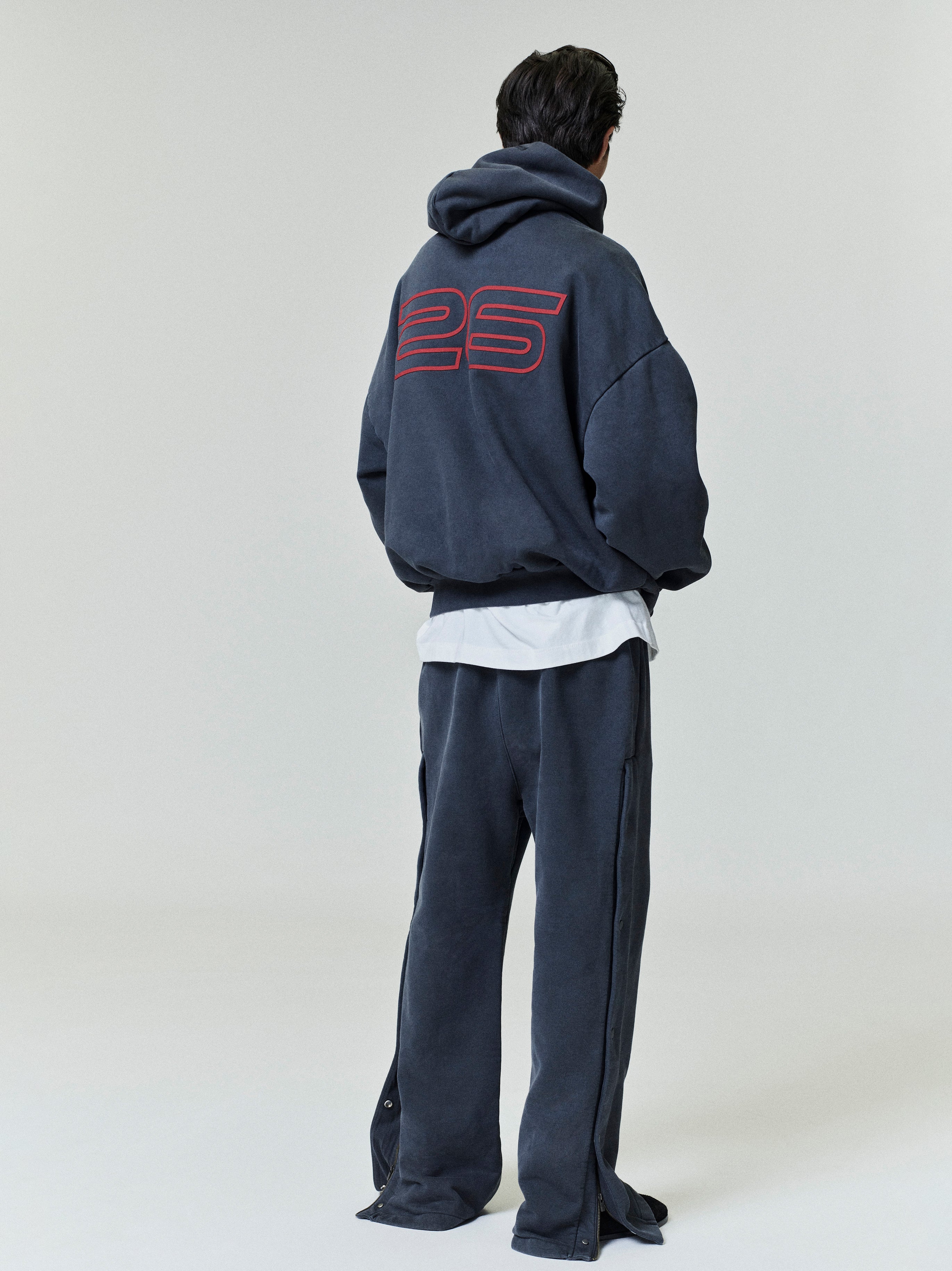 Person wearing a black tracksuit with '25' on the back against a white background