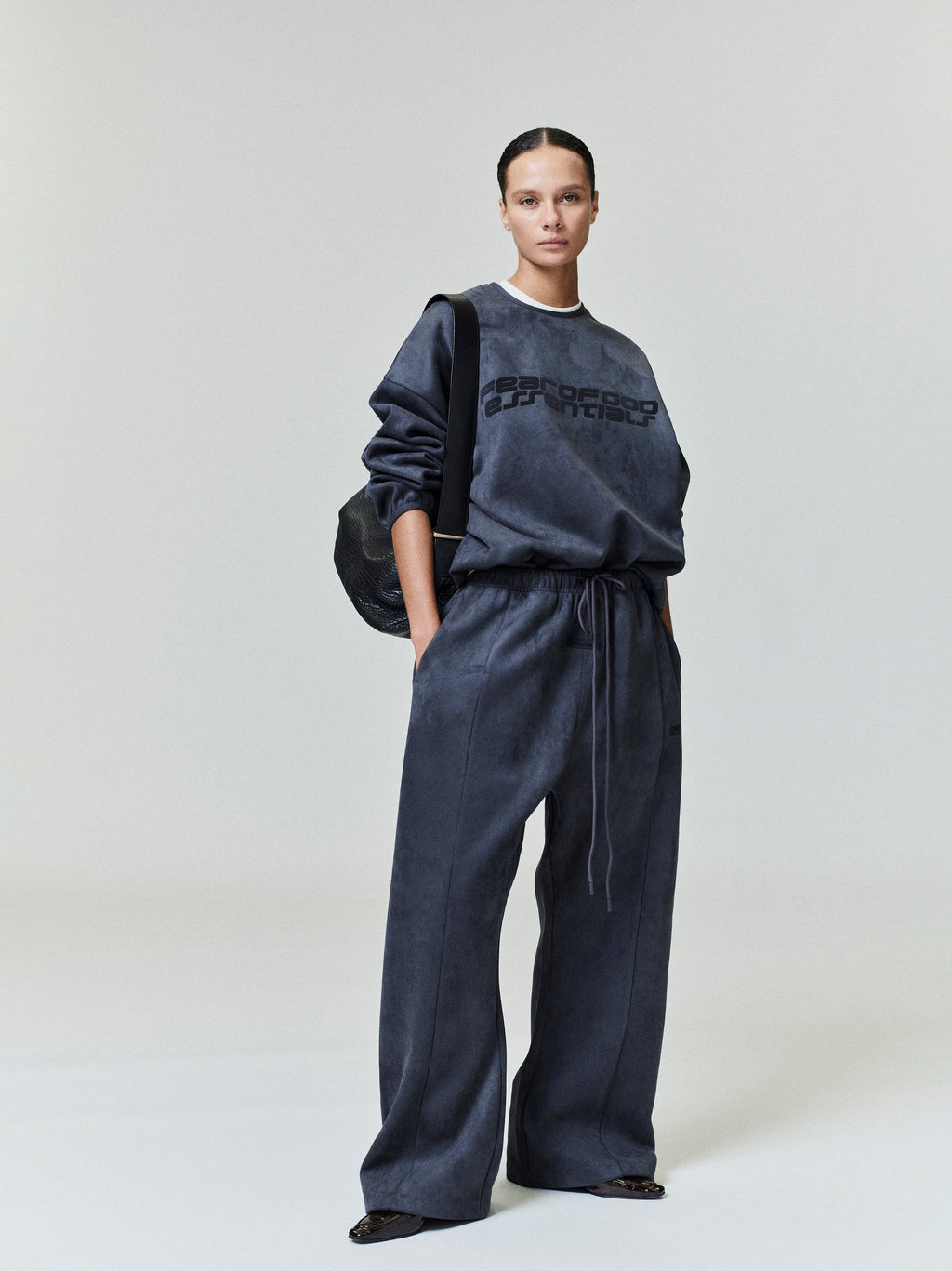 Standing model wearing dark charcoal Suede Fleece Modern Crewneck Sweatshirt and matching wide-leg pants, shot 0042_HO25_FW_L37_0416.jpg