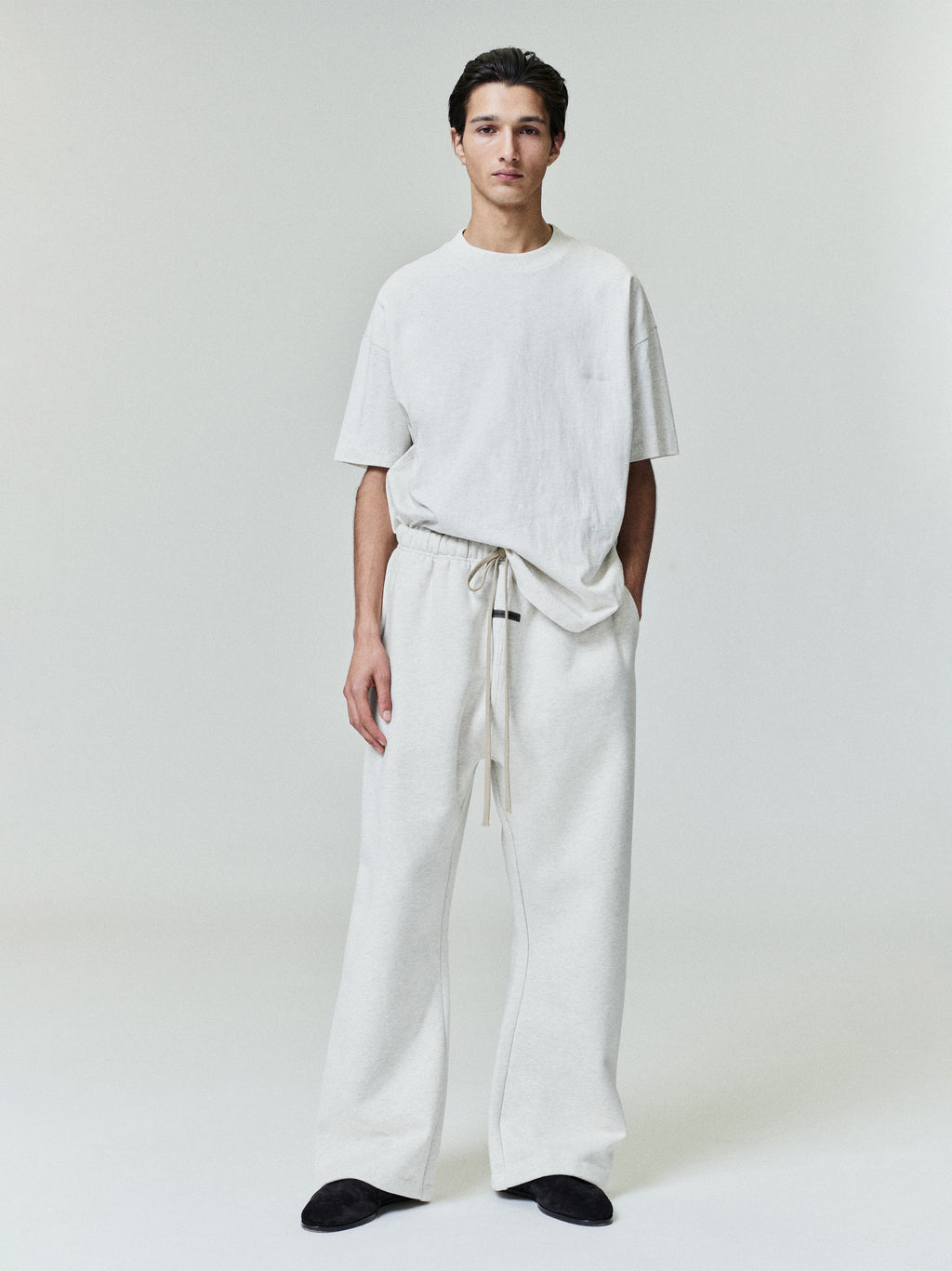 Male model wearing relaxed fit ivory Embroidered Essential Tee and matching wide-leg pants, full front studio view
