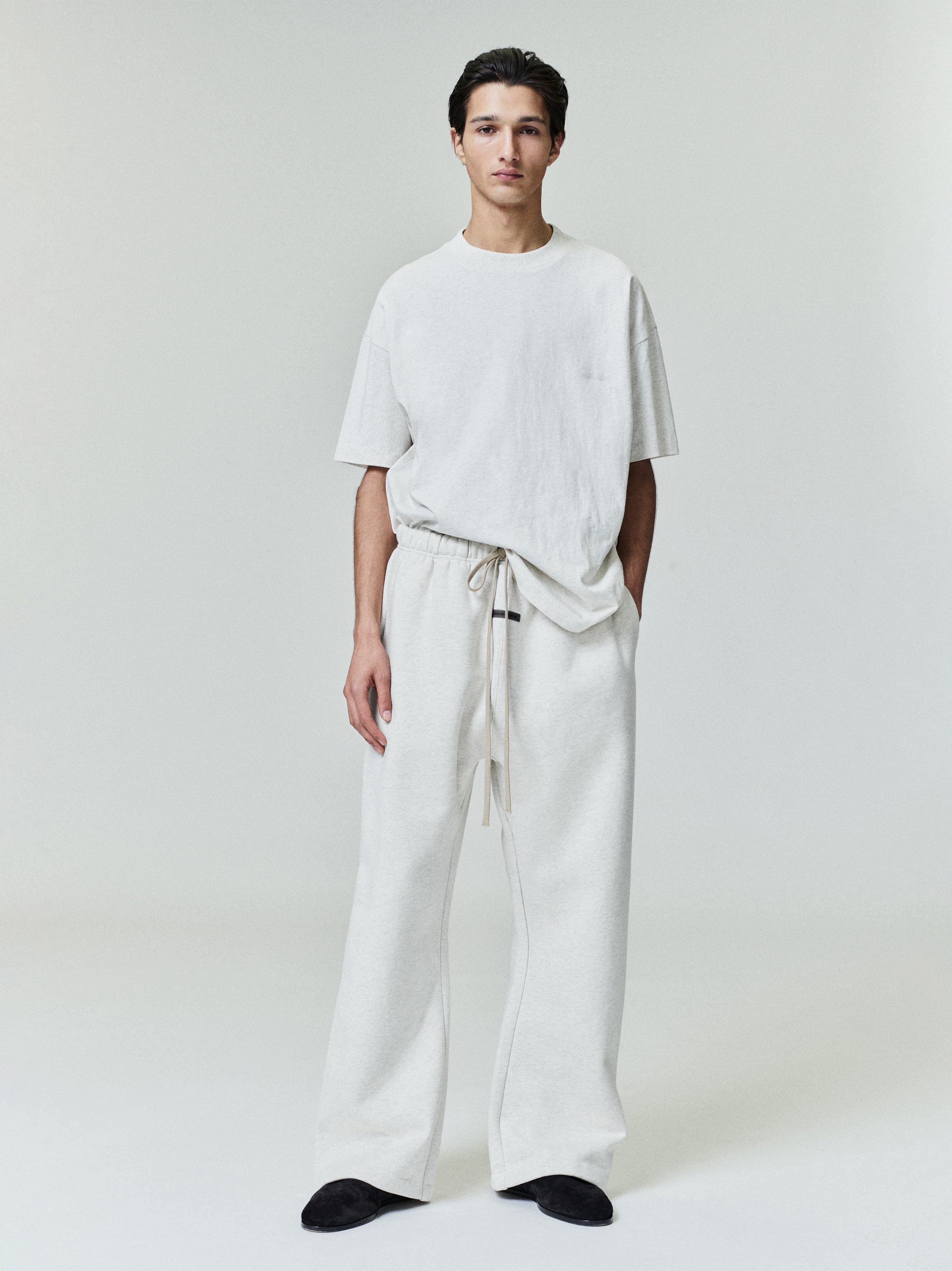 Male model wearing relaxed fit ivory Embroidered Essential Tee and matching wide-leg pants, full front studio view