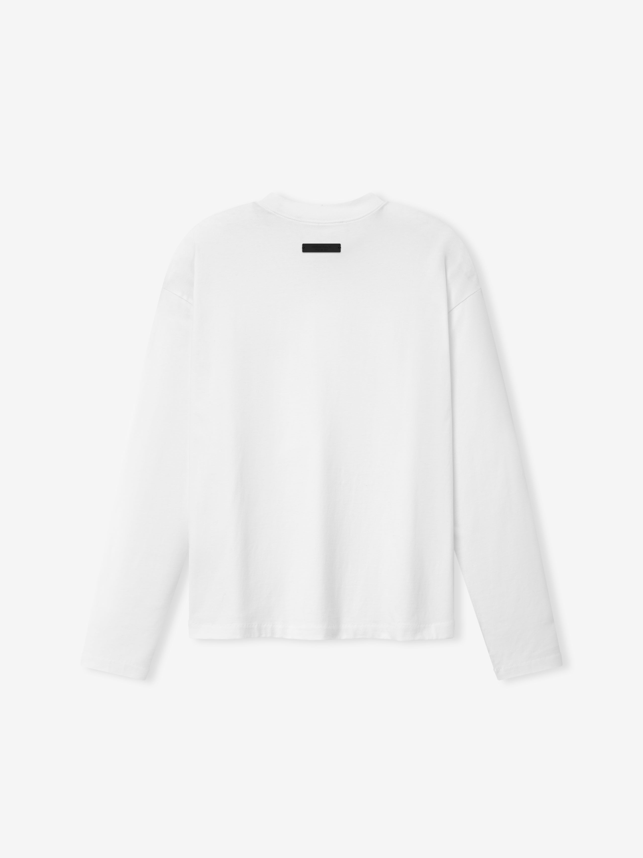 Essentials SS26 Classic Long Sleeve Tee in bright white displayed from the back, featuring a clean, minimal design with a small black rectangular tag at the neckline and a relaxed fit.