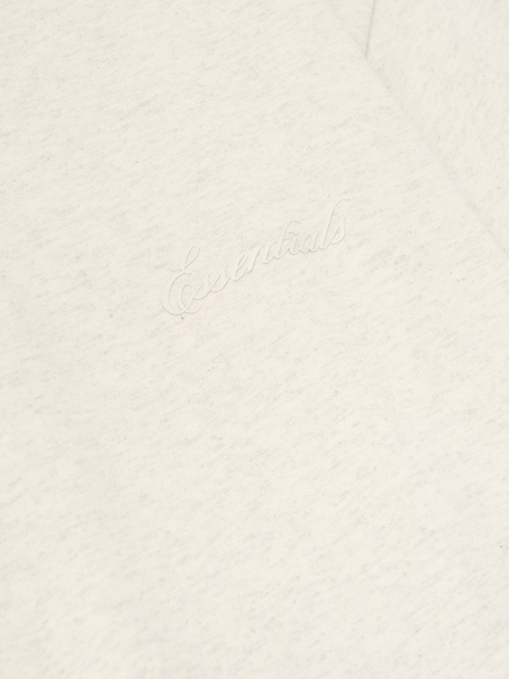 Close-up of oatmeal heather Embroidered Classic Short Sleeve Tee highlighting tonal "Essentials" script embroidery on chest area