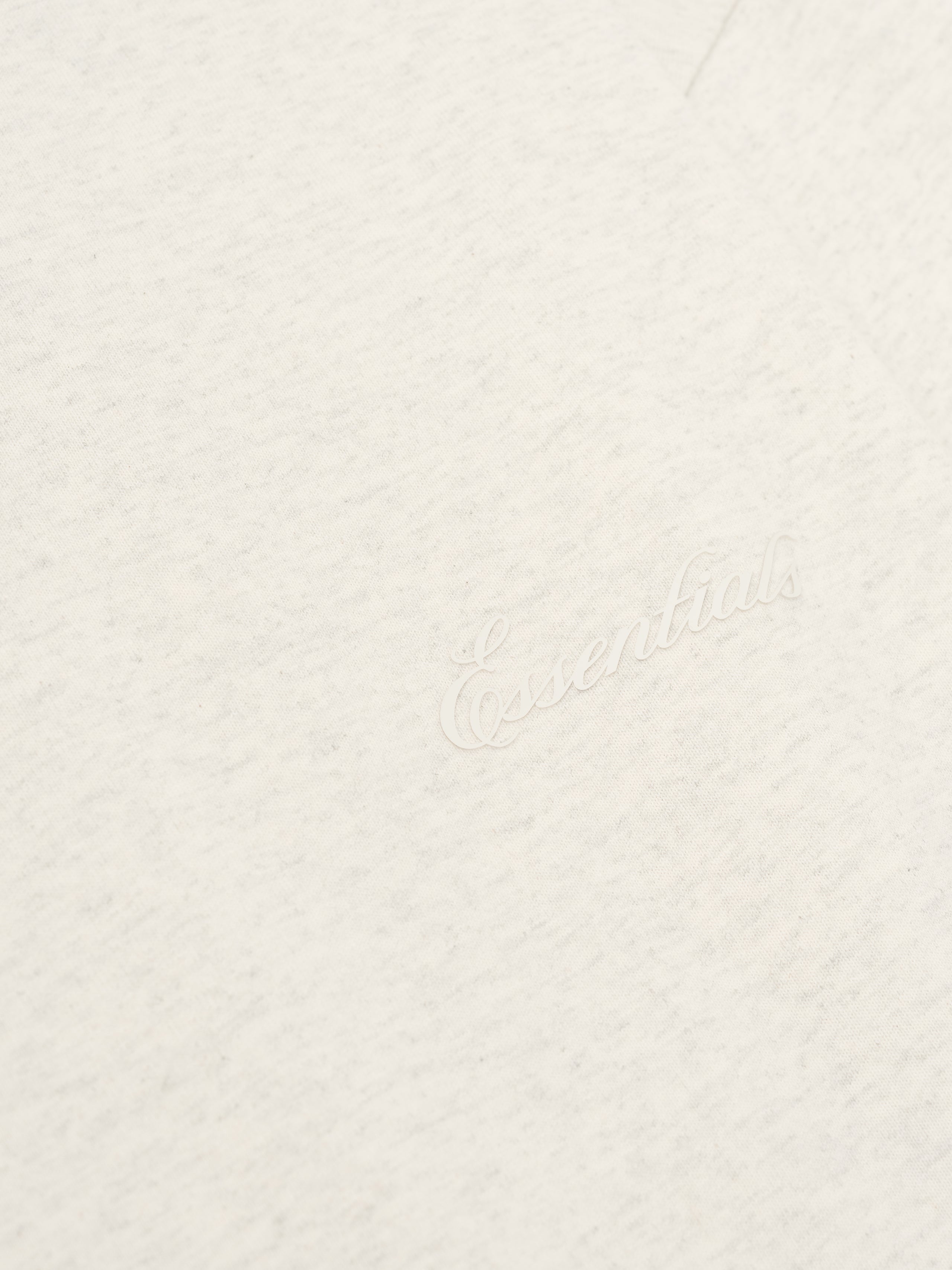 Close-up of oatmeal heather Embroidered Classic Long Sleeve Tee showing tonal Essentials logo detail, gallery image 0