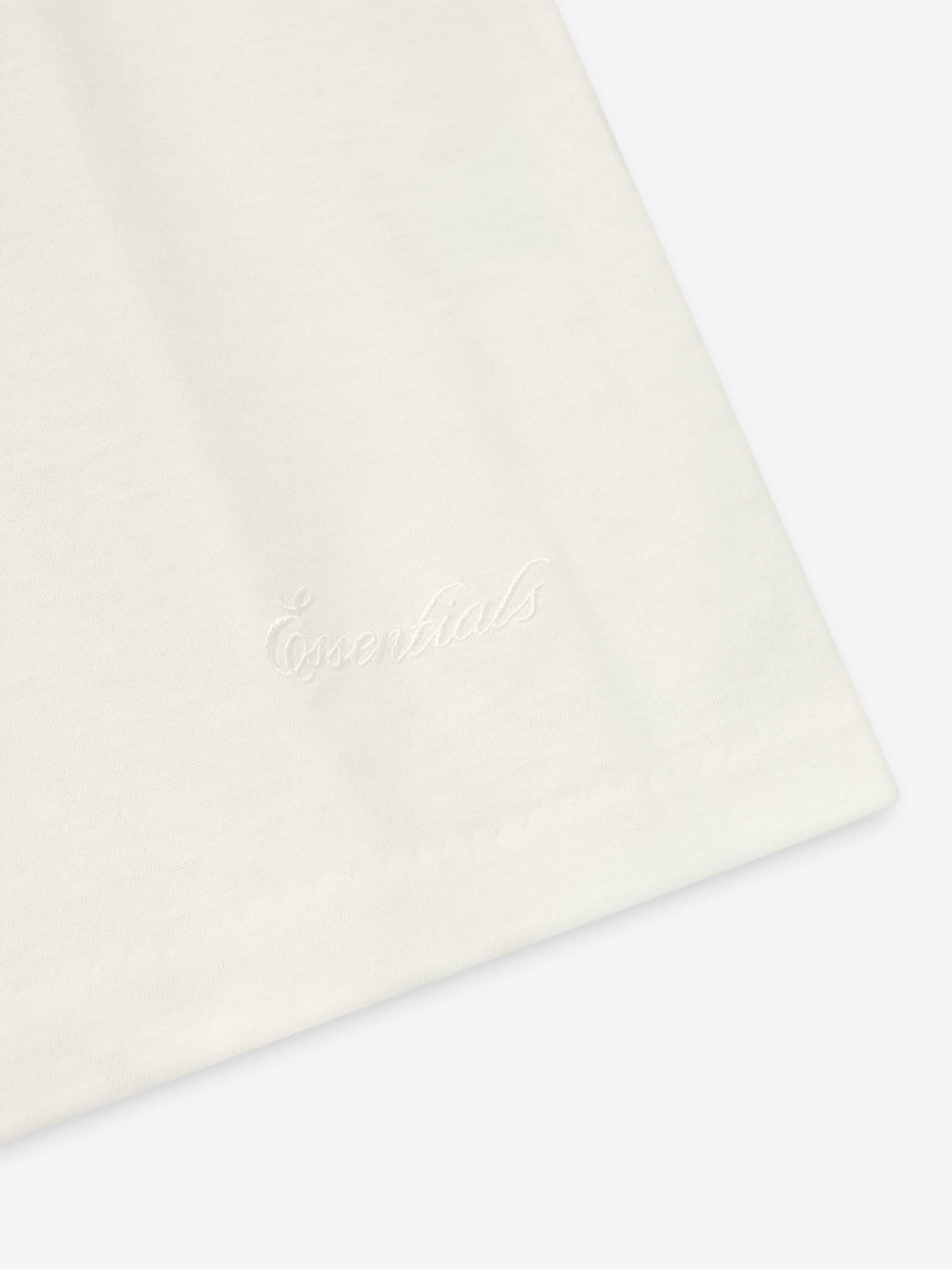 Close-up of ivory Embroidered Essential Tank showing subtle tonal "Essentials" script embroidery near hem, gallery image 0