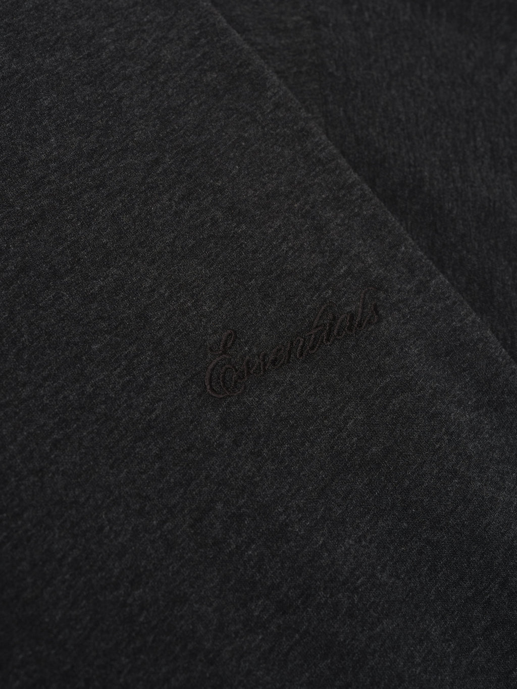 Close-up of vintage black Embroidered Essential Tee highlighting subtle tonal Essentials embroidery on soft fabric surface