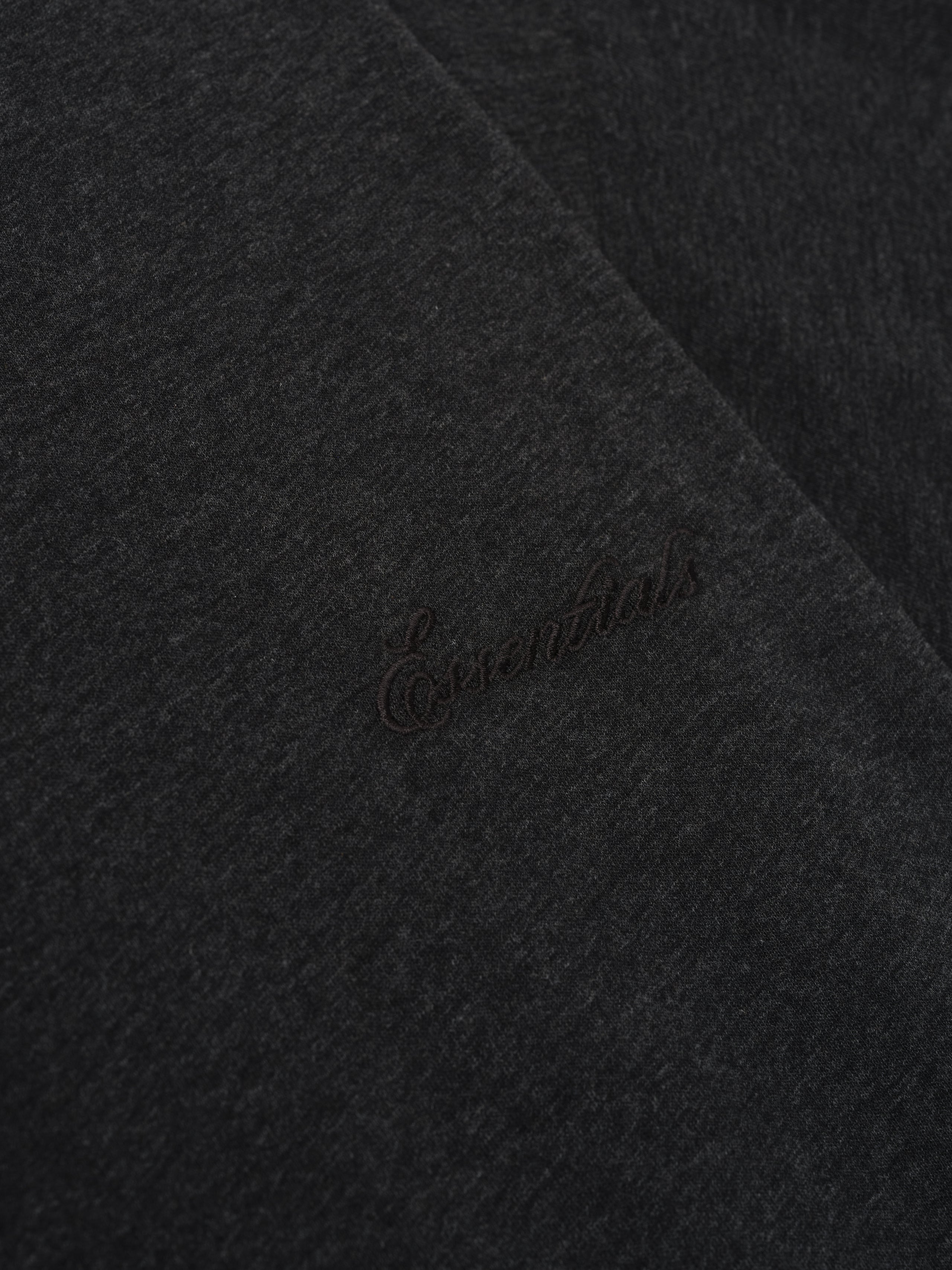 Close-up of vintage black Embroidered Essential Tee highlighting subtle tonal Essentials embroidery on soft fabric surface