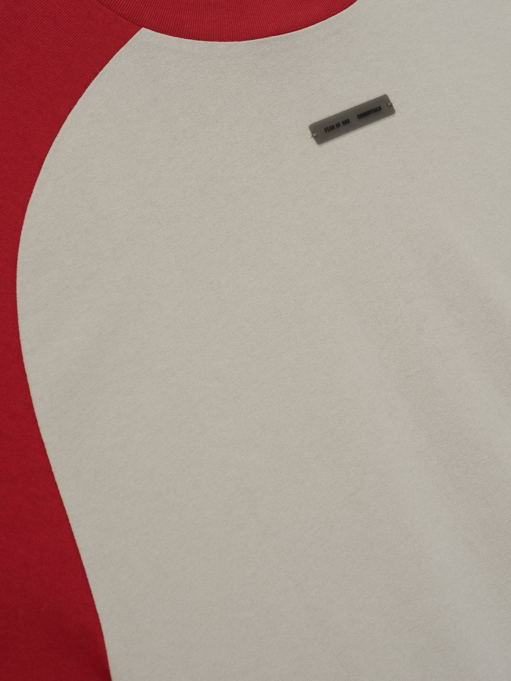 Close-up of smoke grey baseball tee with crimson raglan sleeve and small rectangular label near chest area.