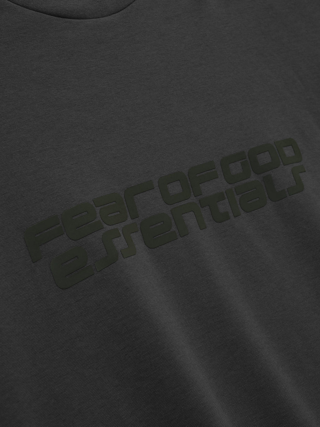 Close-up of iron grey Ponte 90s Tee featuring subtle embossed Fear of God Essentials logo on smooth soft fabric