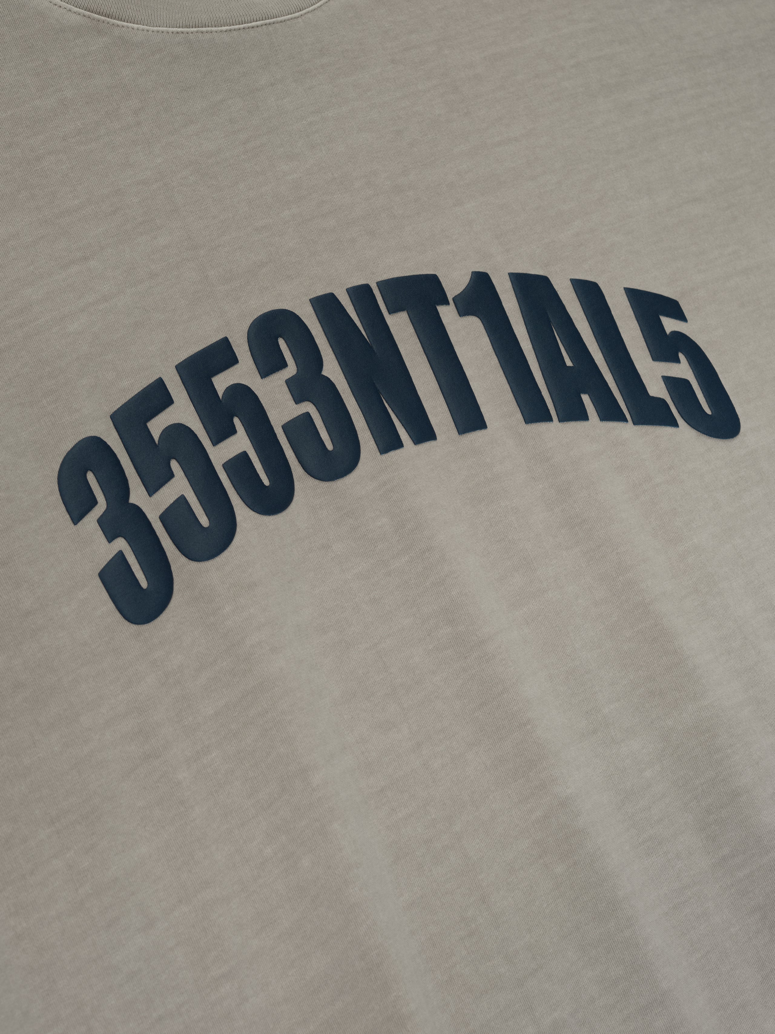 Close-up of smoke grey New York 90s Tee with curved navy blue alphanumeric print on soft cotton fabric