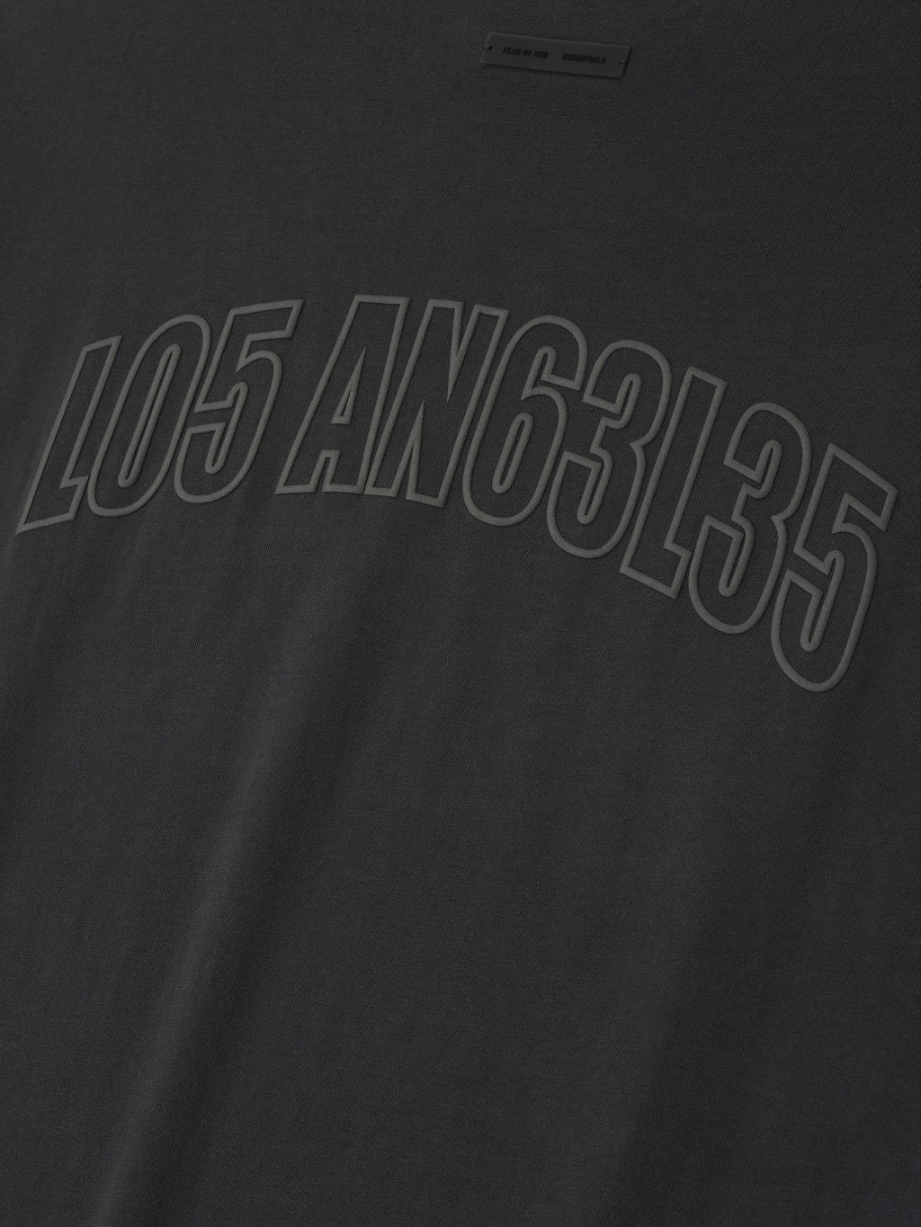 Close-up of vintage black Los Angeles 90s Tee featuring embossed mixed numeric and letter print across soft fabric surface