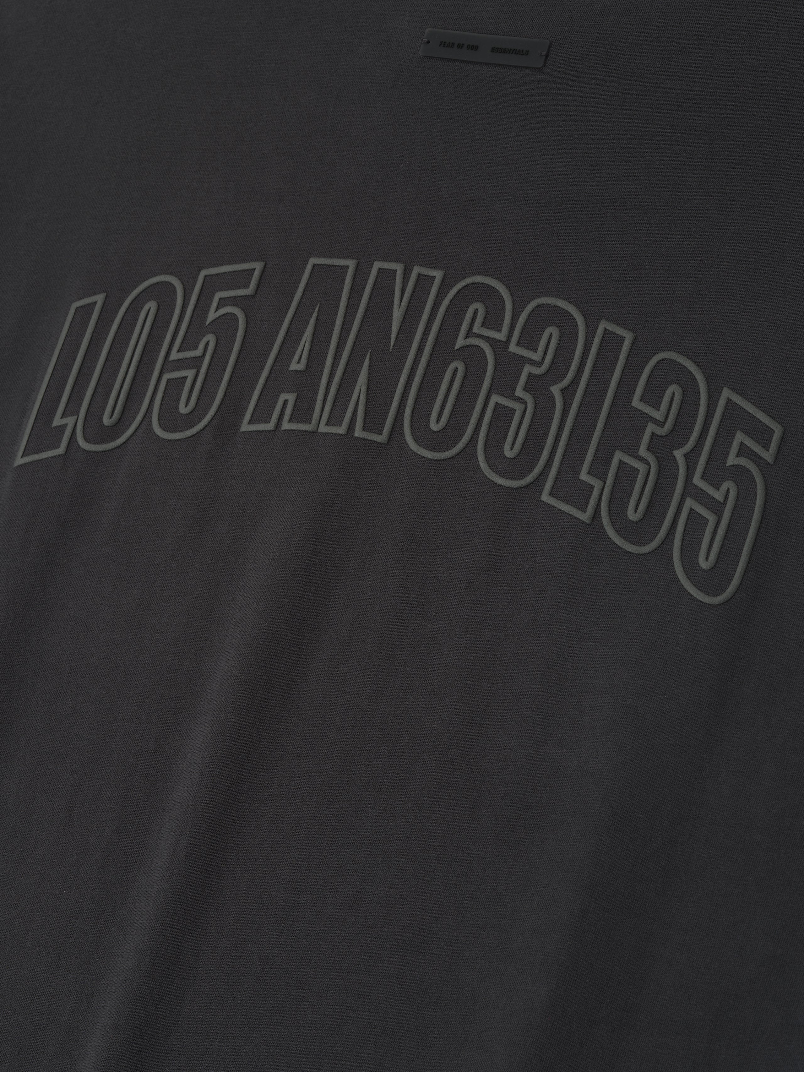 Close-up of vintage black Los Angeles 90s Tee featuring embossed mixed numeric and letter print across soft fabric surface