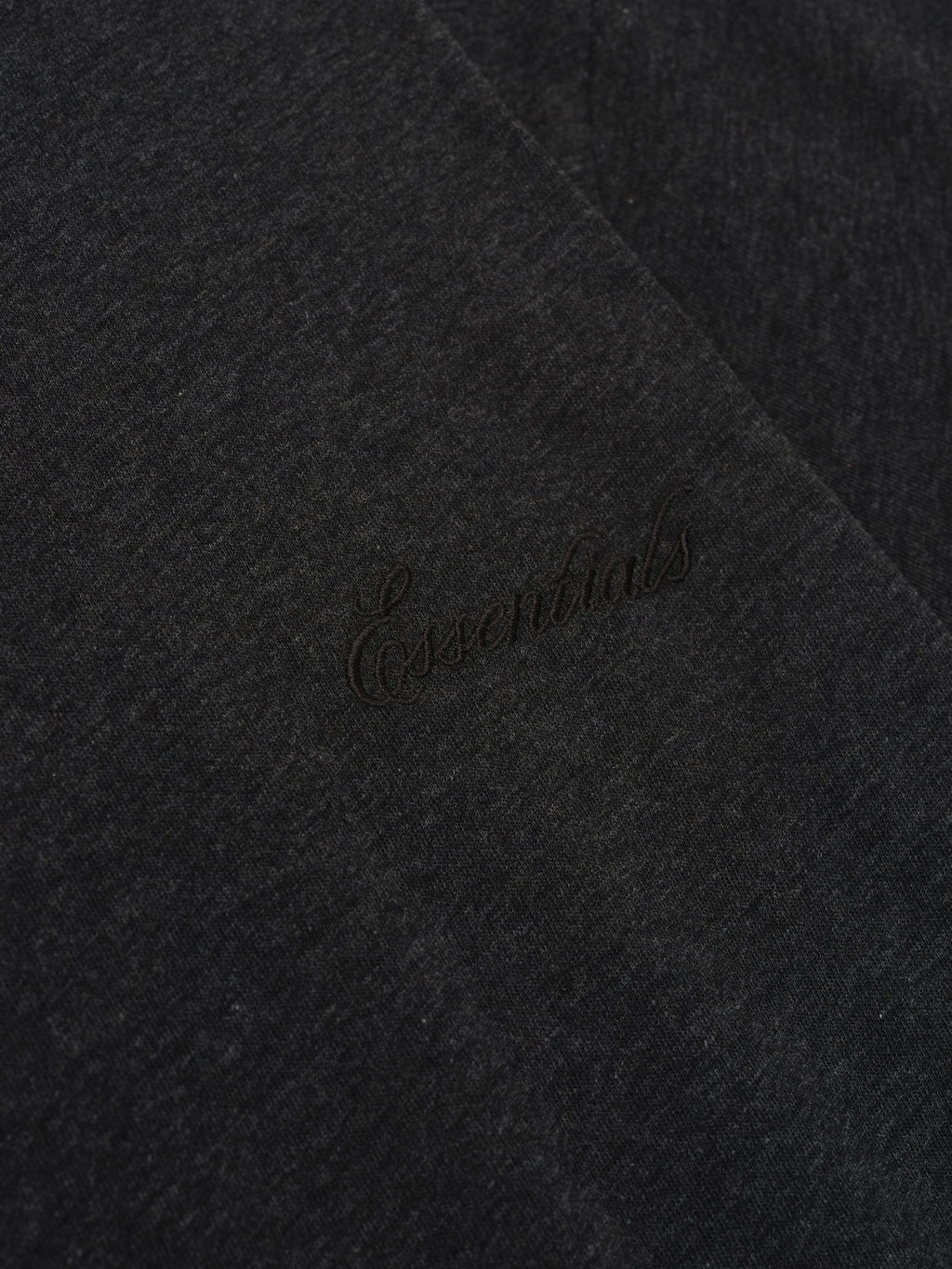 Close-up of vintage black Womens Classic Tee showing subtle tonal "Essentials" embroidery on soft fabric surface
