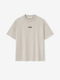 front view of light beige medium-weight cotton jersey tee with rib-knit crewneck and small rectangular logo patch on chest
