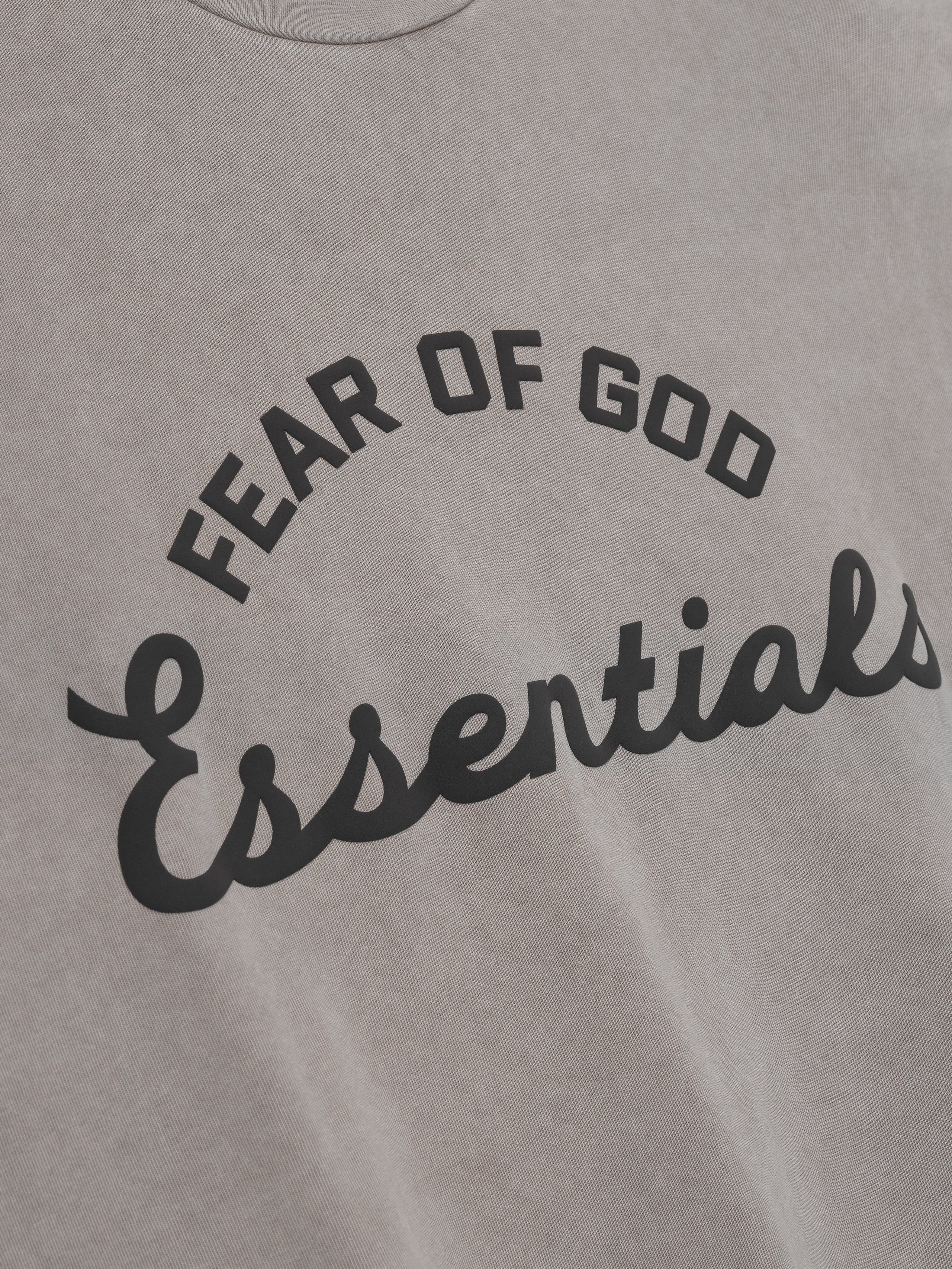 Gray t-shirt with 'Fear of God Essentials' text in black on a plain background