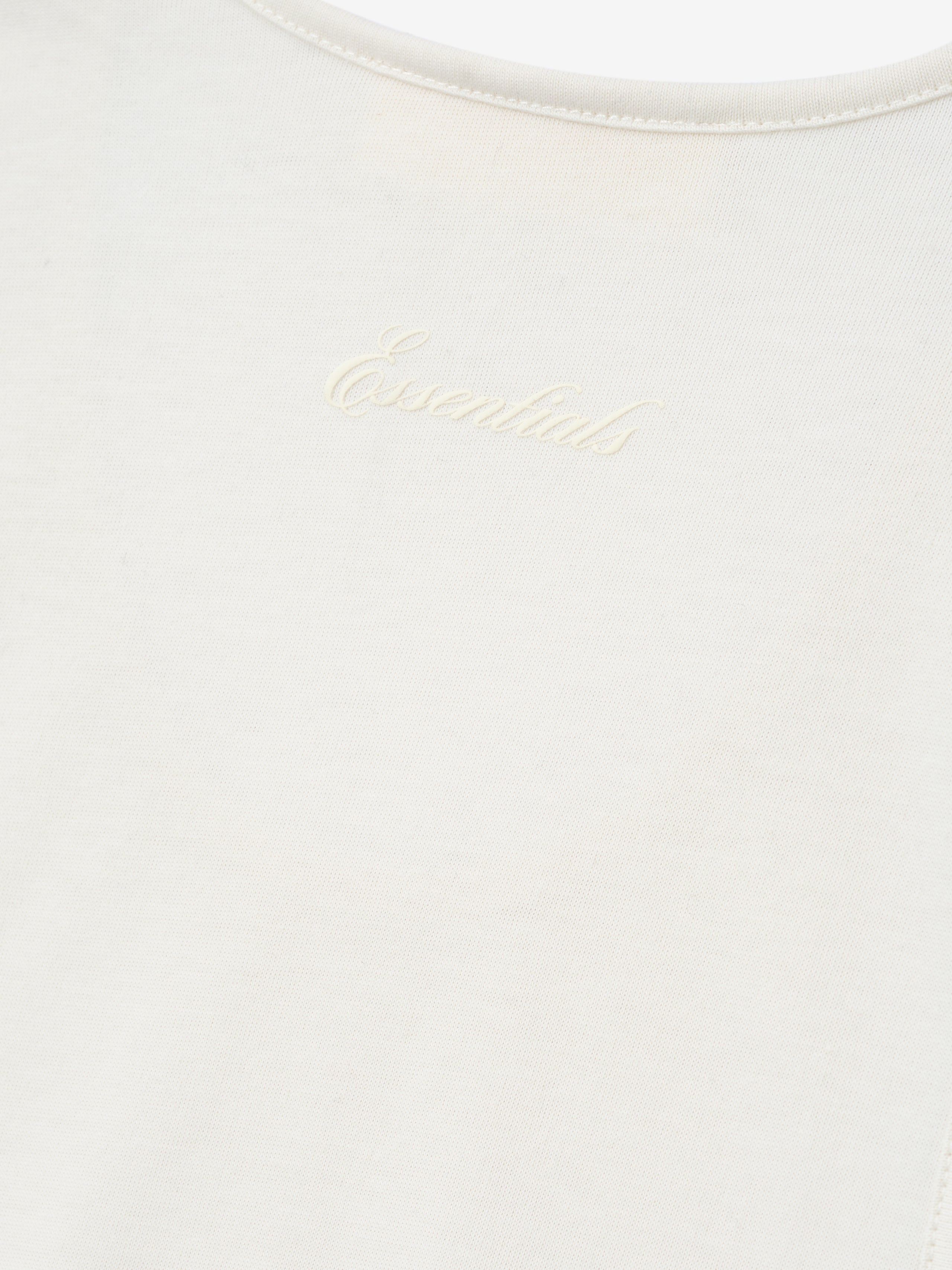 Close-up of a white shirt with 'Essential' script logo