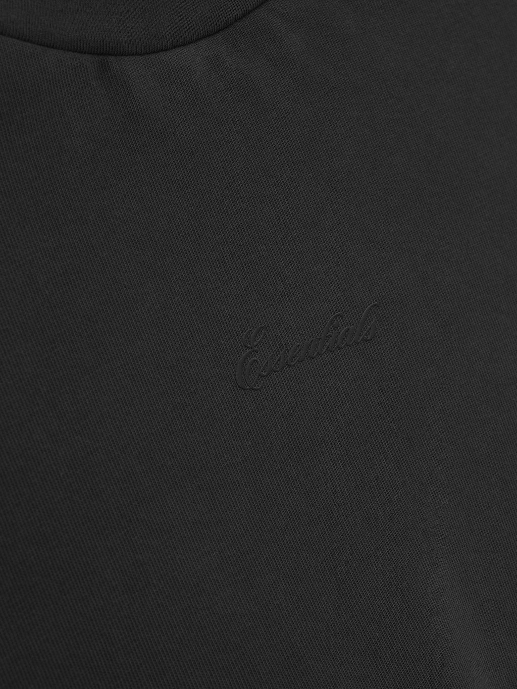 close-up of black heavyweight cotton jersey with embroidered subtle Essentials signature logo on chest