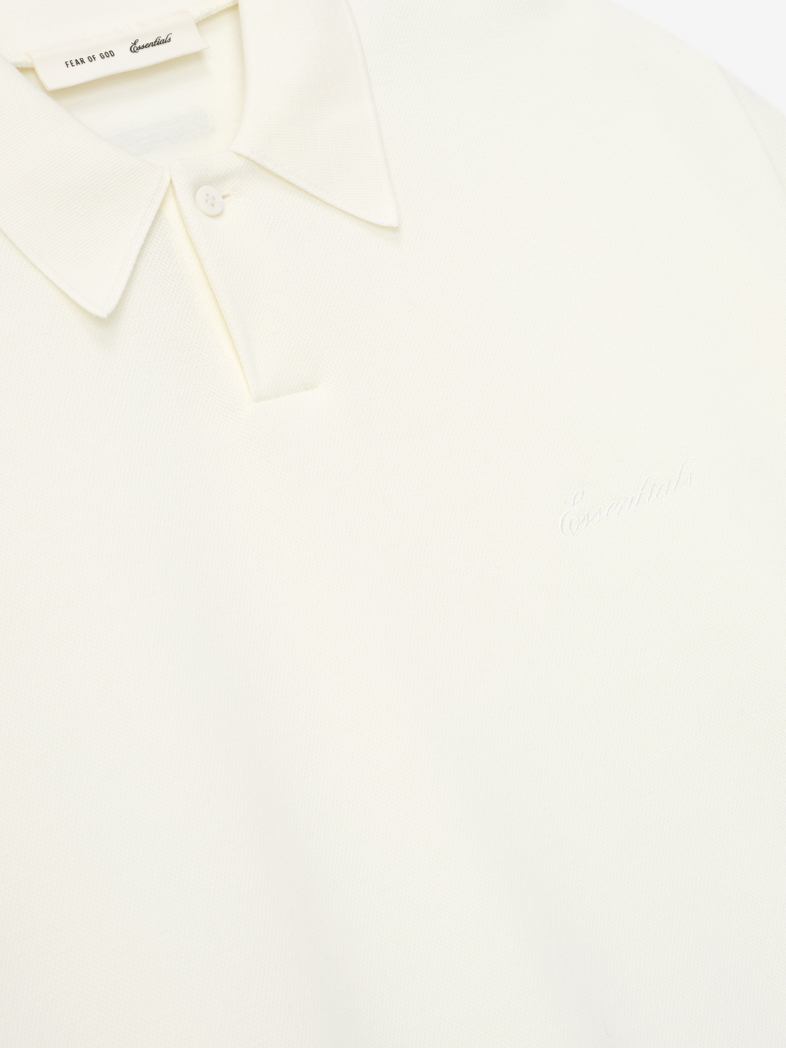 close-up of off-white medium-weight cotton poly pique polo with classic collar and subtle embossed branding on chest