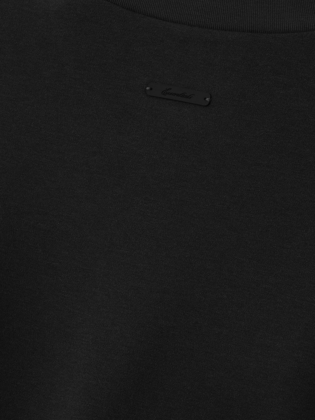 Close up of tee shirt with black essentials script label