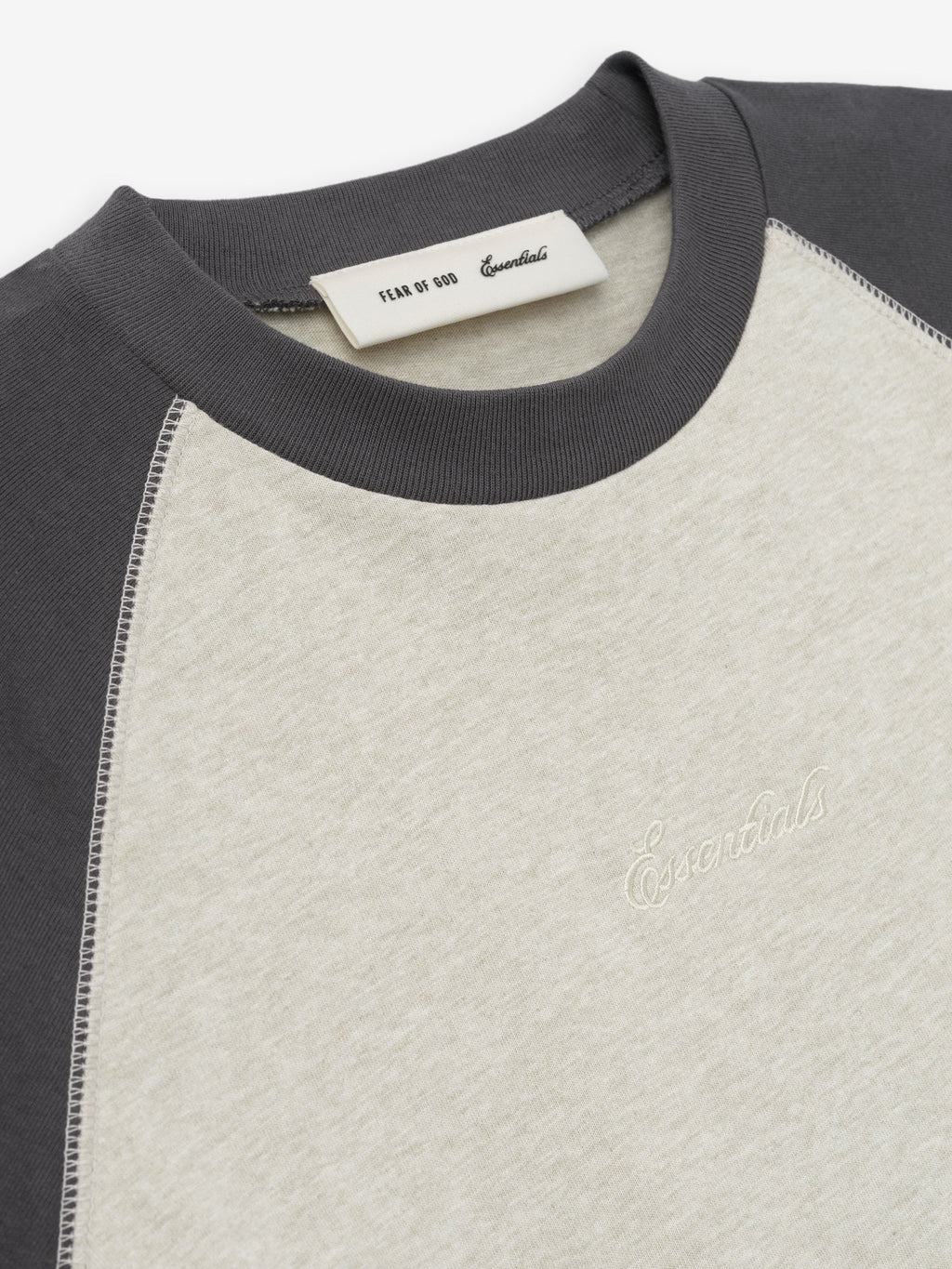 close-up of cream and charcoal raglan sleeve cotton baseball tee with rib-knit crewneck and embroidered Essentials logo