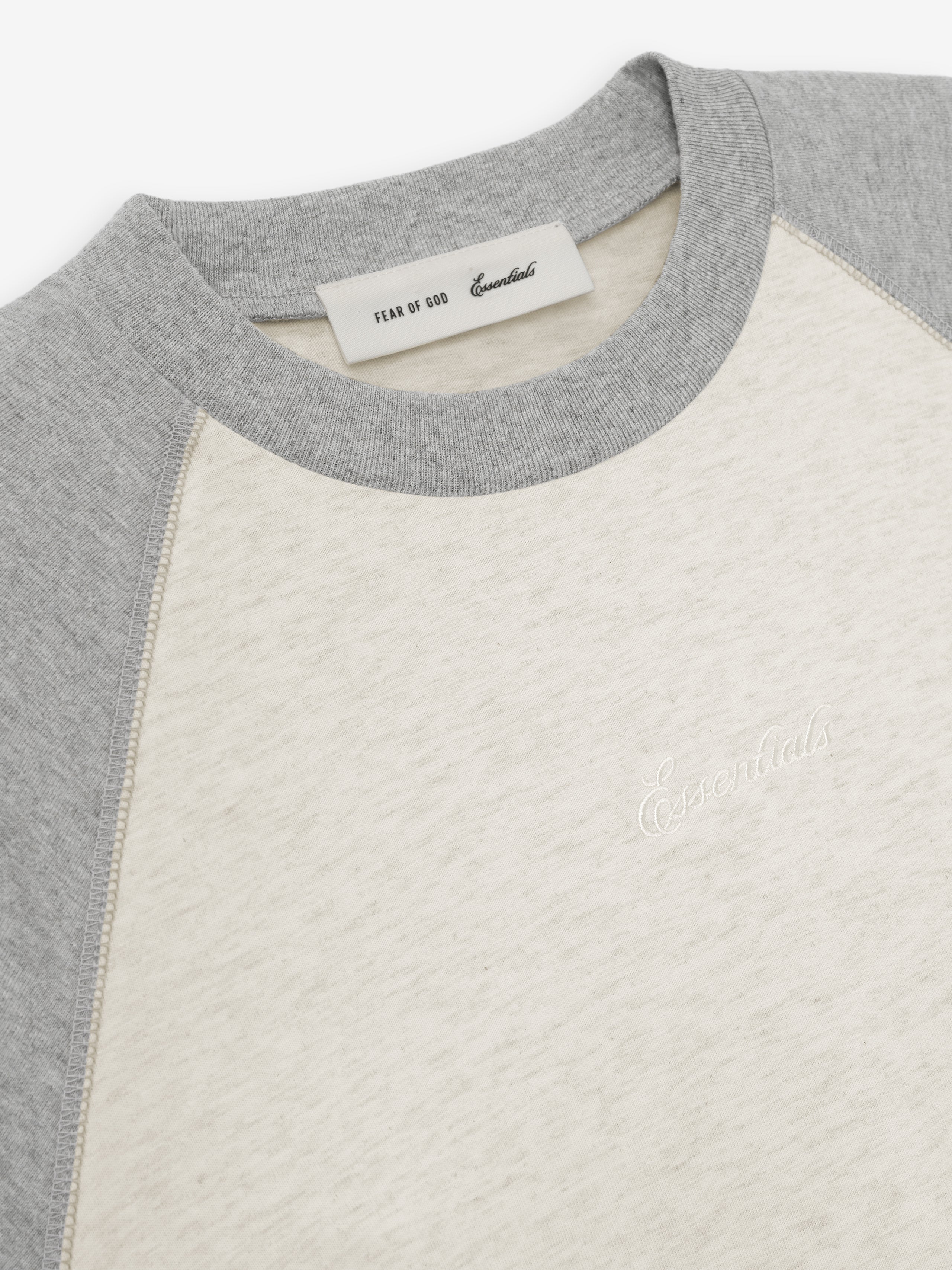 close-up of light cream classic fit baseball tee with gray raglan sleeves and embroidered Essentials logo on chest