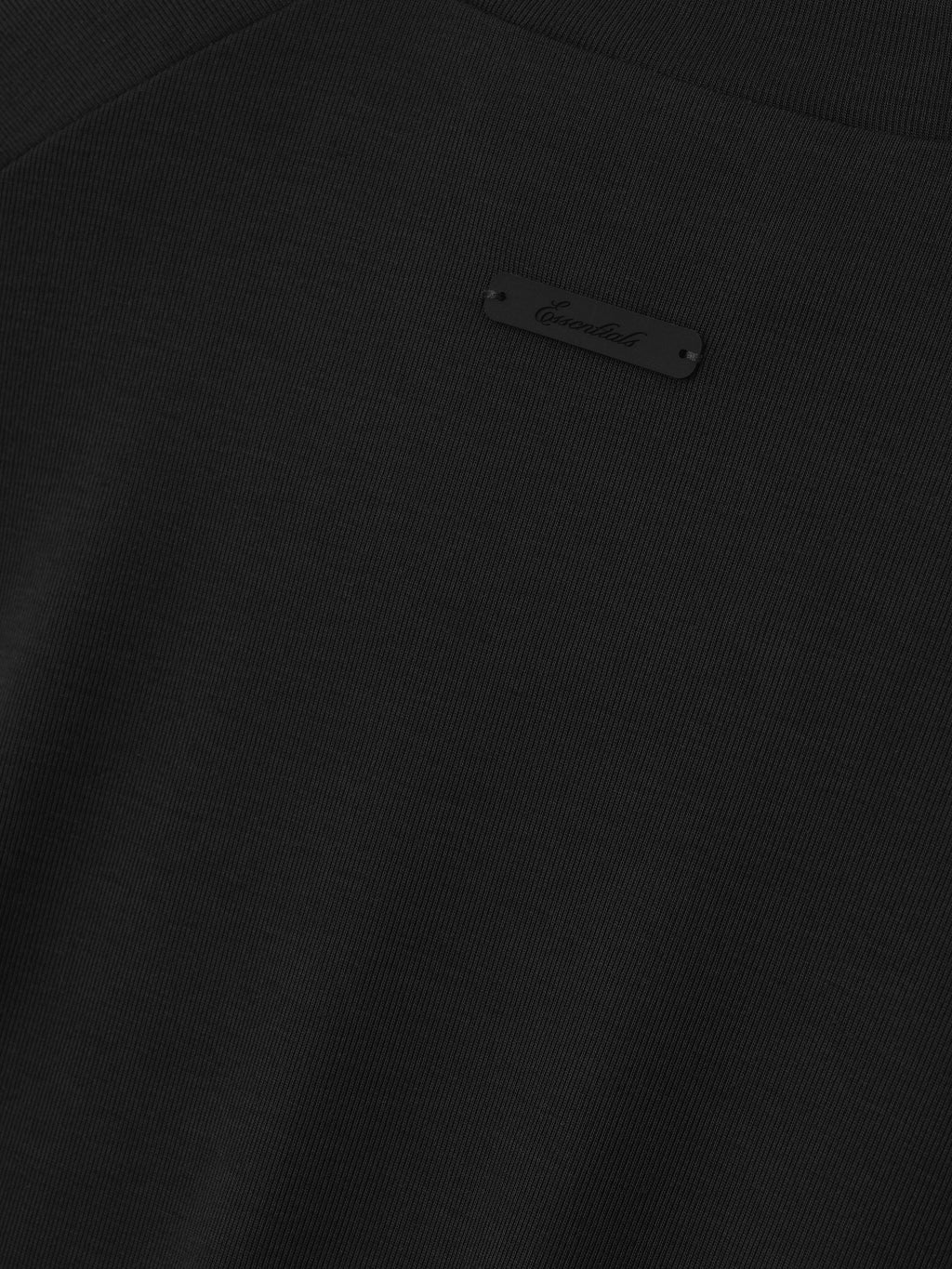 Close-up of a black tee with Signature "Essentials" tag sewn on the back.