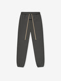 Charcoal gray sweatpants featuring elastic waistband, long beige drawstrings, and cuffed ankles in a slim classic fit