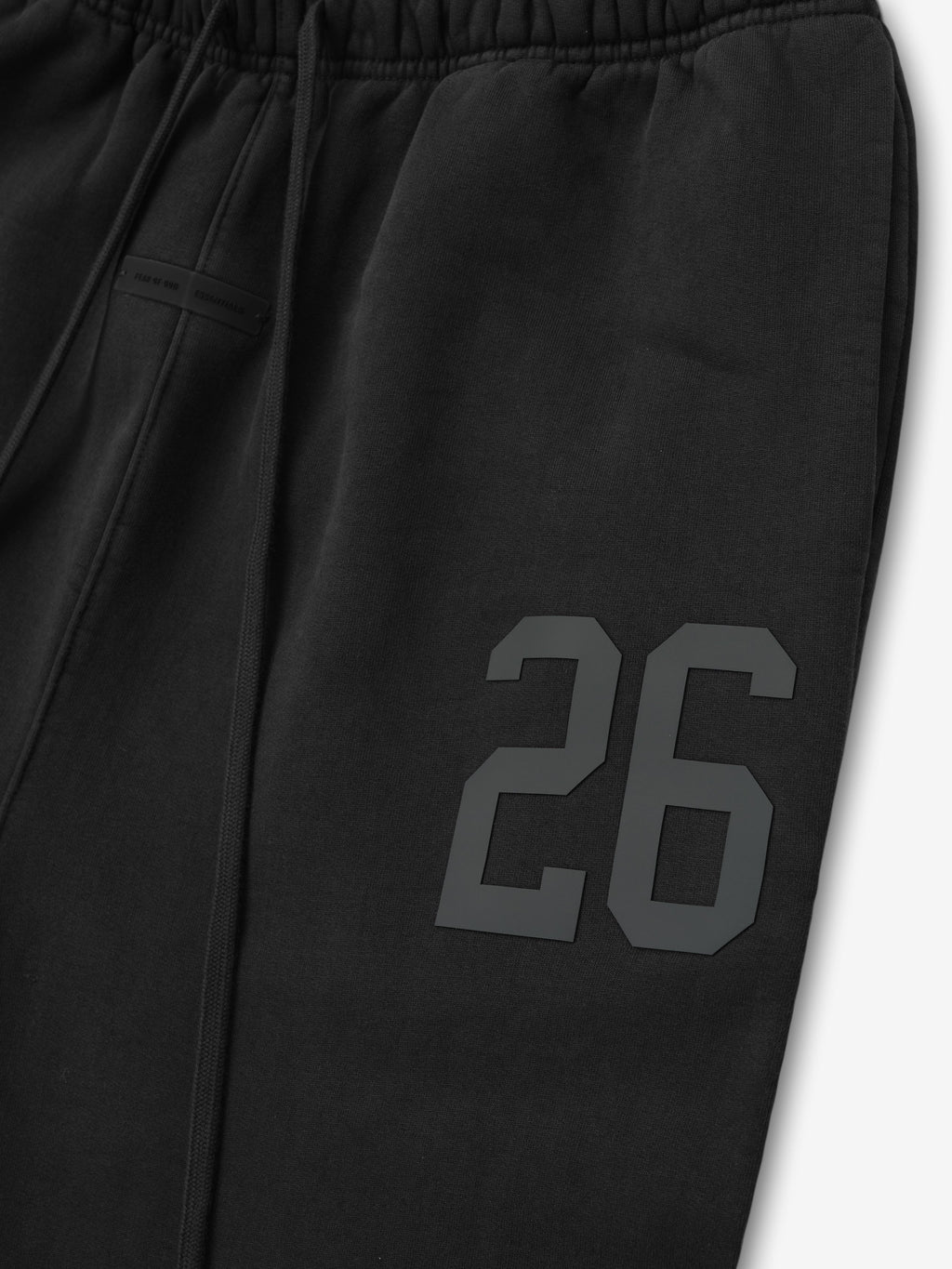 Close-up of vintage black heavy fleece sweatpant leg with embossed number 26 detail and elastic waistband