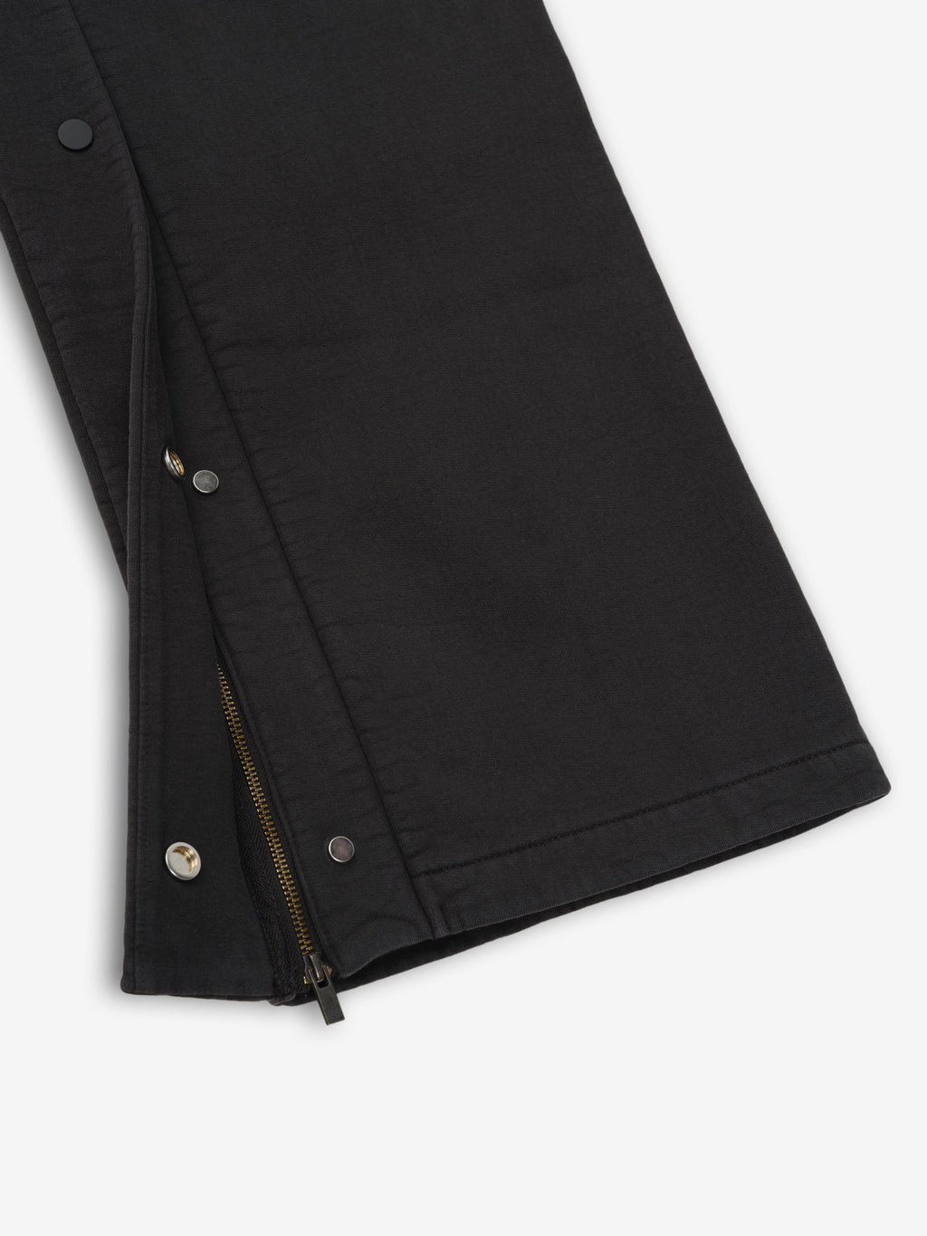 Close-up of vintage black heavy fleece tearaway sweatpant leg with partially unzipped side zipper and snap buttons