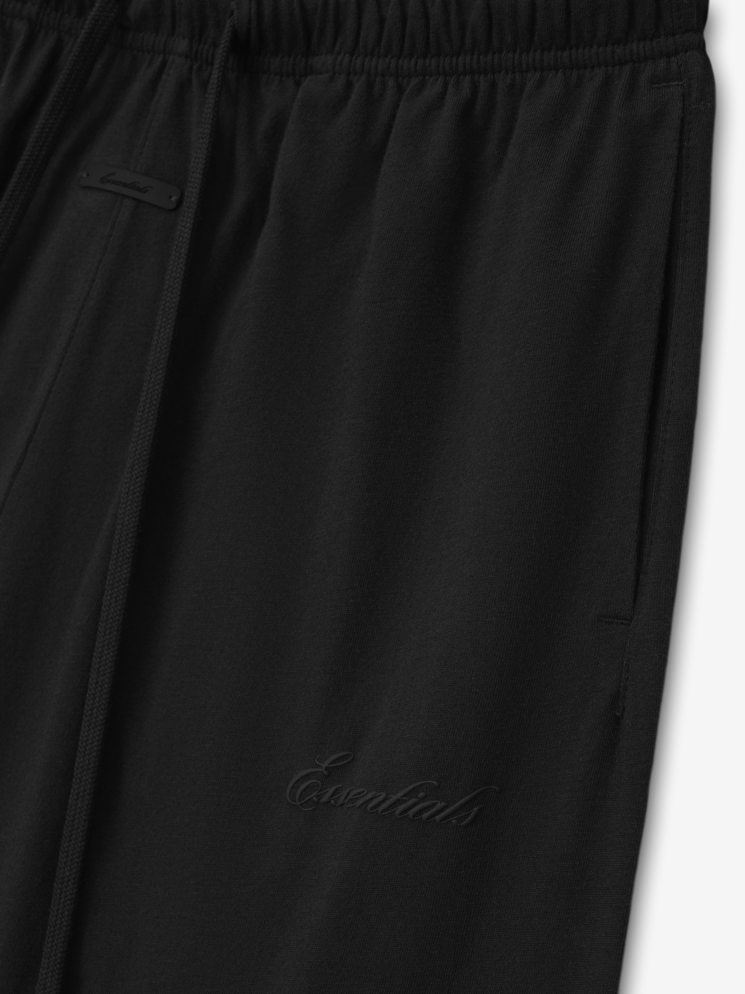 close-up of black women's lightweight cotton sweatpants with elastic waistband and subtle embroidered branding detail