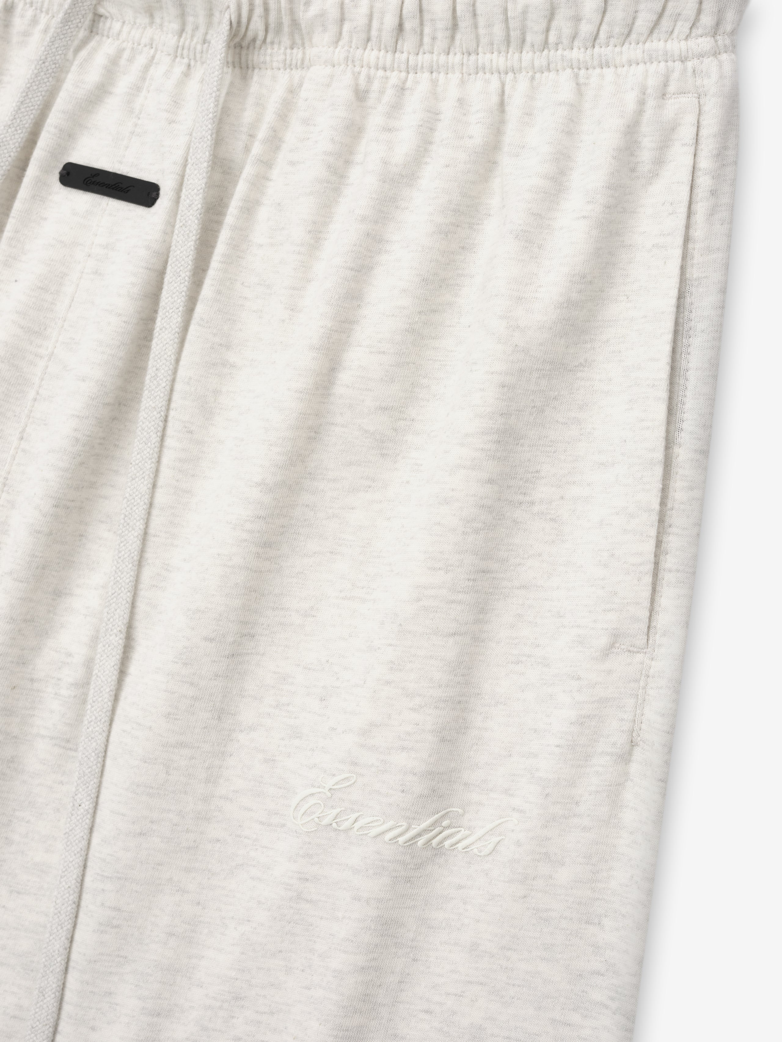 close-up of light beige women's cotton jersey sweatpants with elastic waistband and subtle embroidered Essentials logo