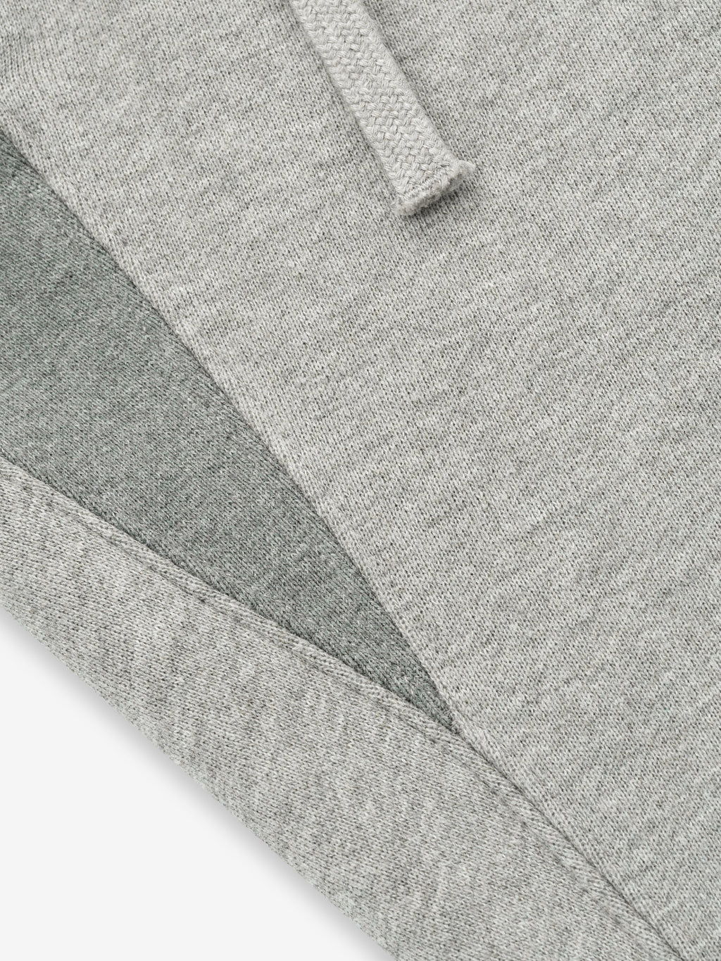 close-up of light grey core fleece fabric with stitched edges and drawstring detail on sweatpants