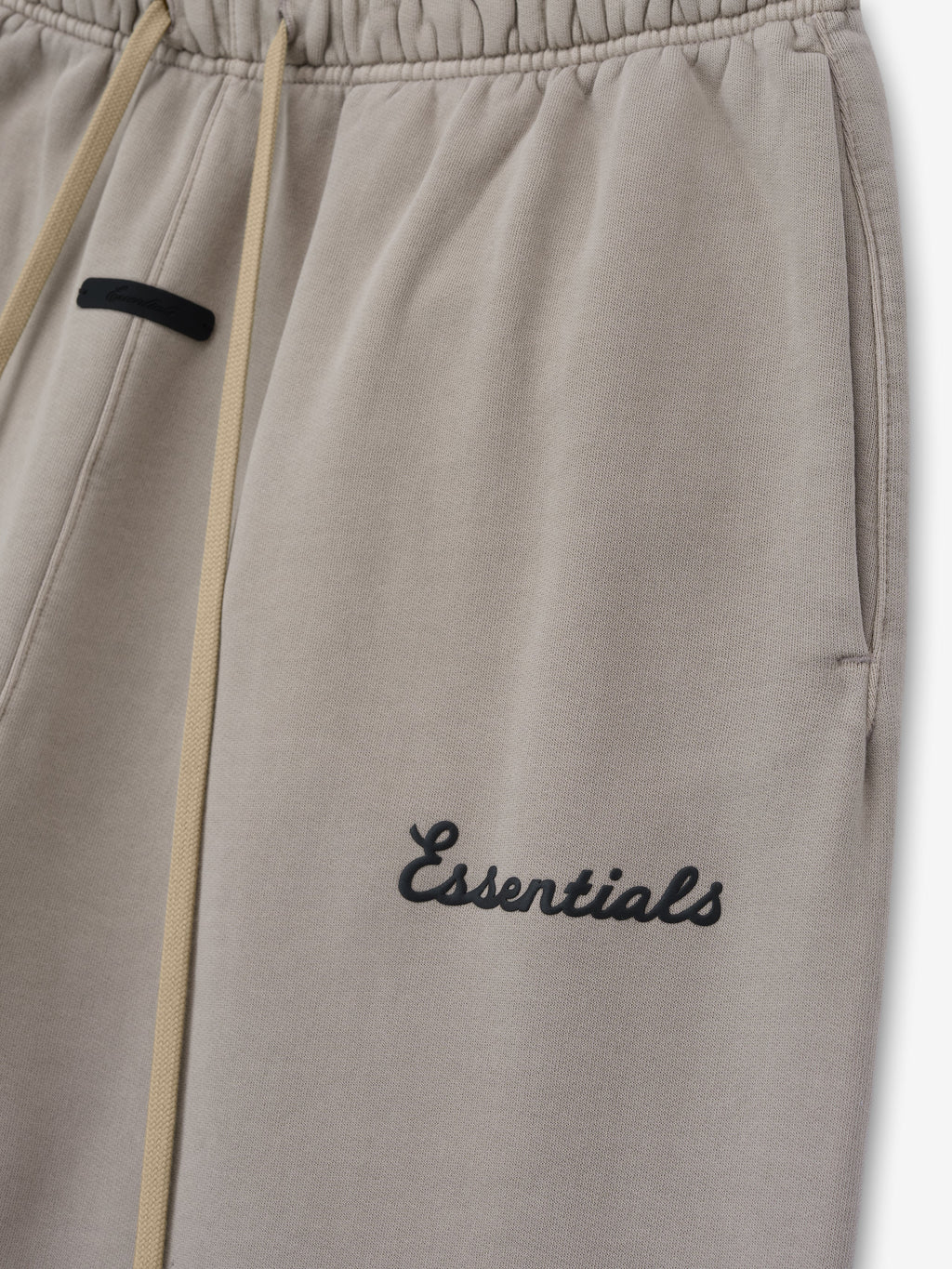 Grey sweatpants with 'essentials' embroidery on a white background