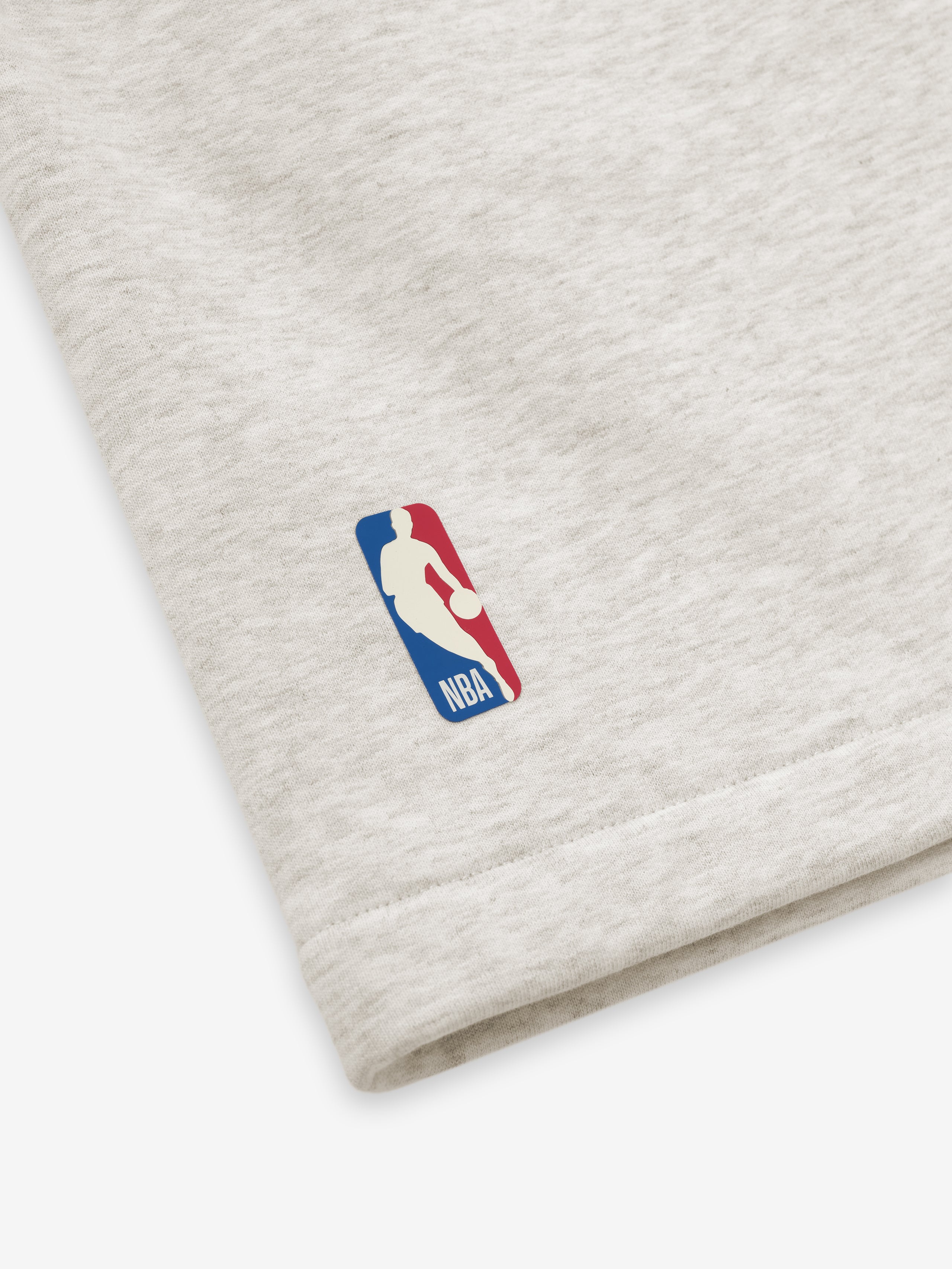 light beige heavyweight cotton fleece sweatshorts with subtle NBA logo near hem and structured relaxed leg silhouette