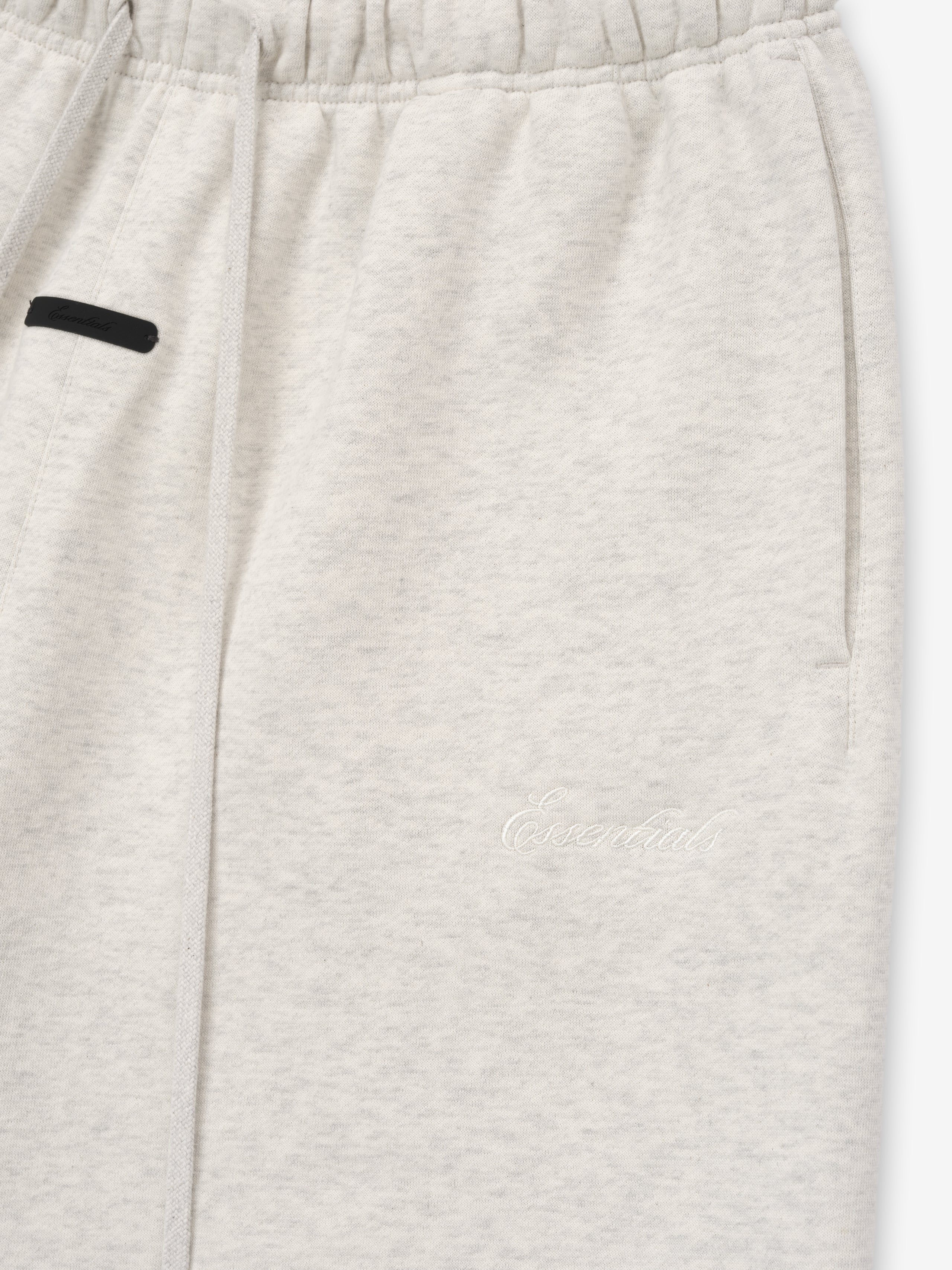 Close-up of light gray shorts with a black patch on a white background