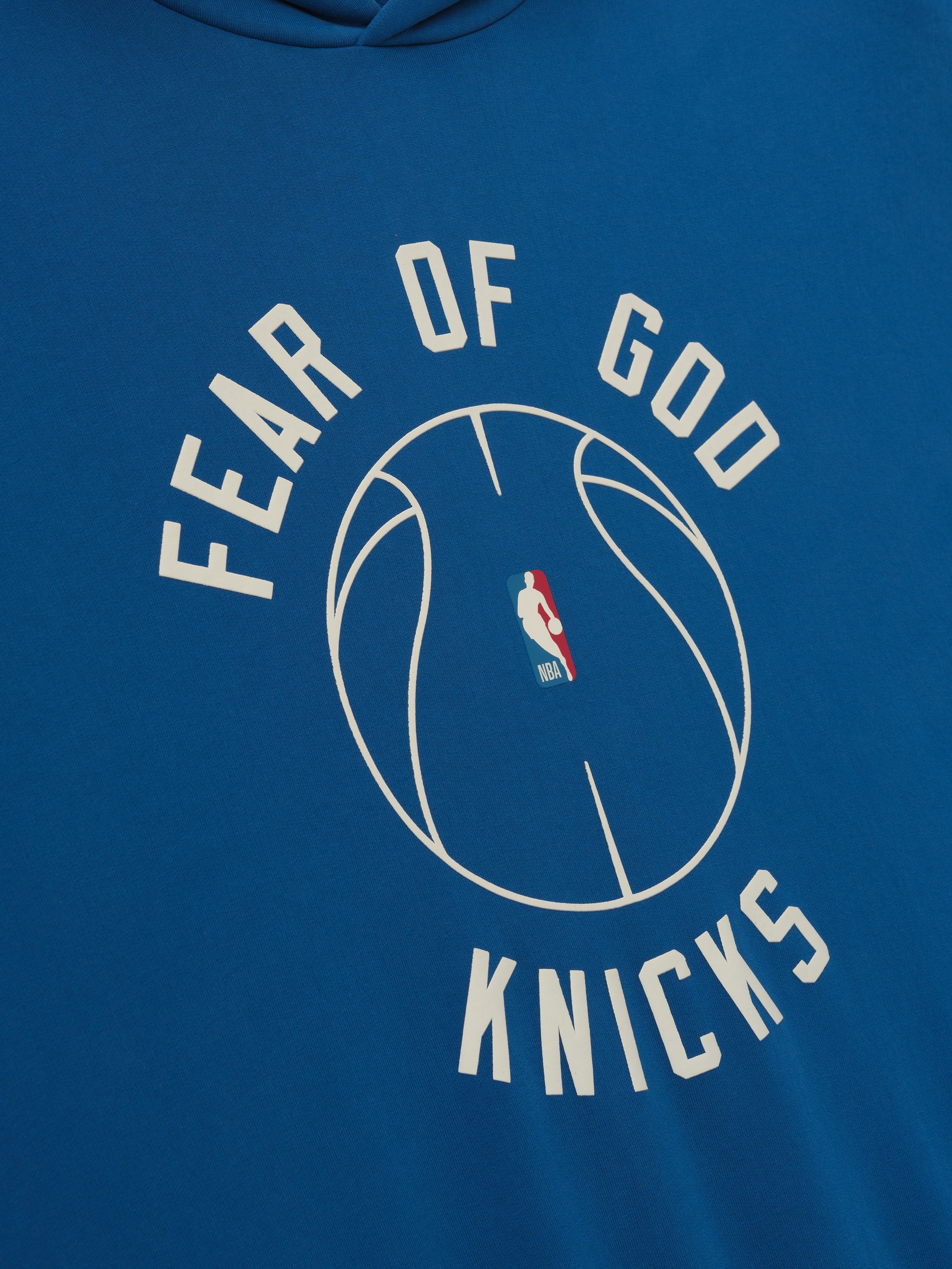 blue hoodie with puff-printed Fear of God Knicks text and NBA basketball graphic on front center