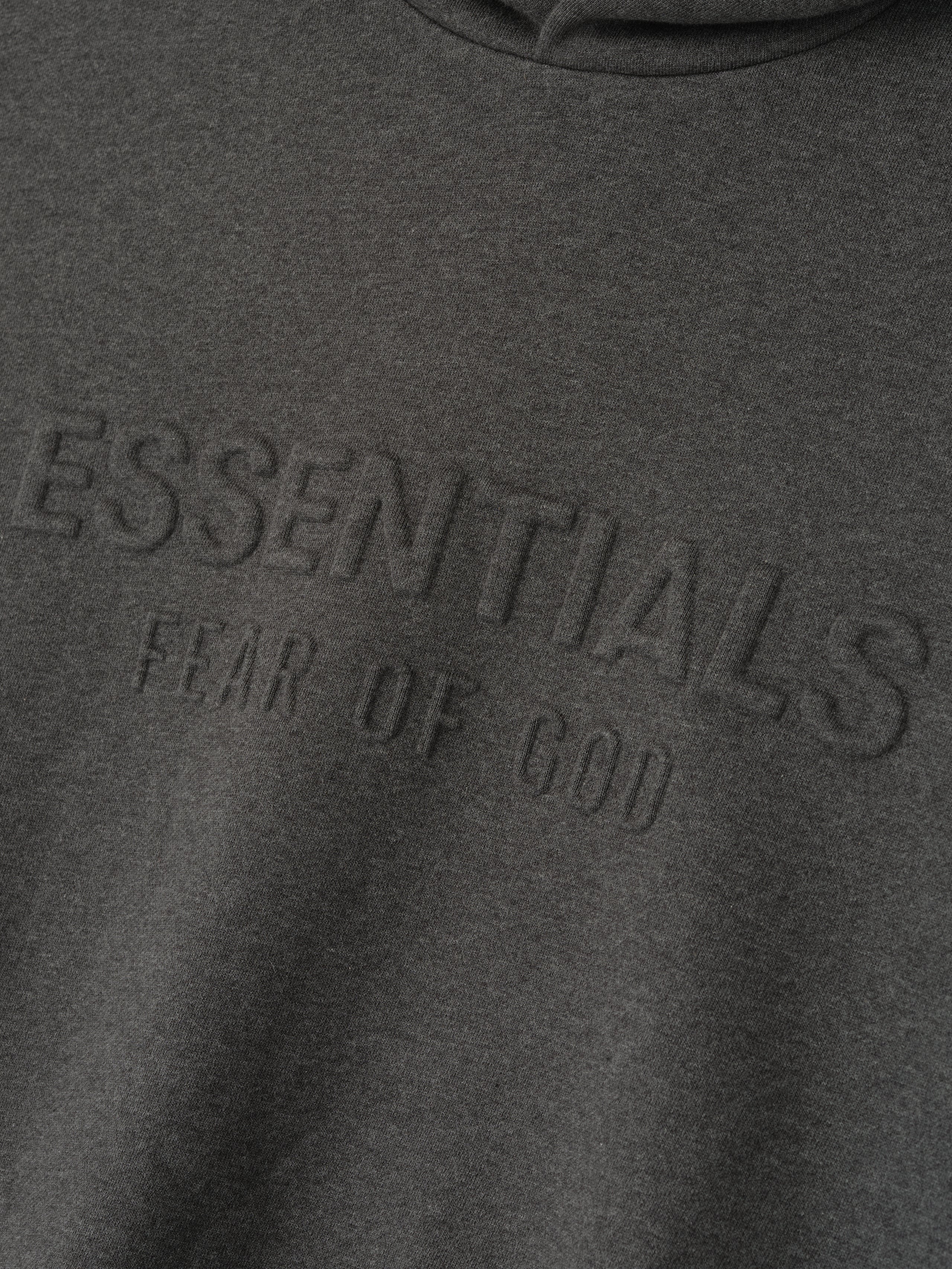 Close-up of charcoal heather Embossed Essentials Classic Hoodie showing raised ESSENTIALS Fear of God logo on chest detail